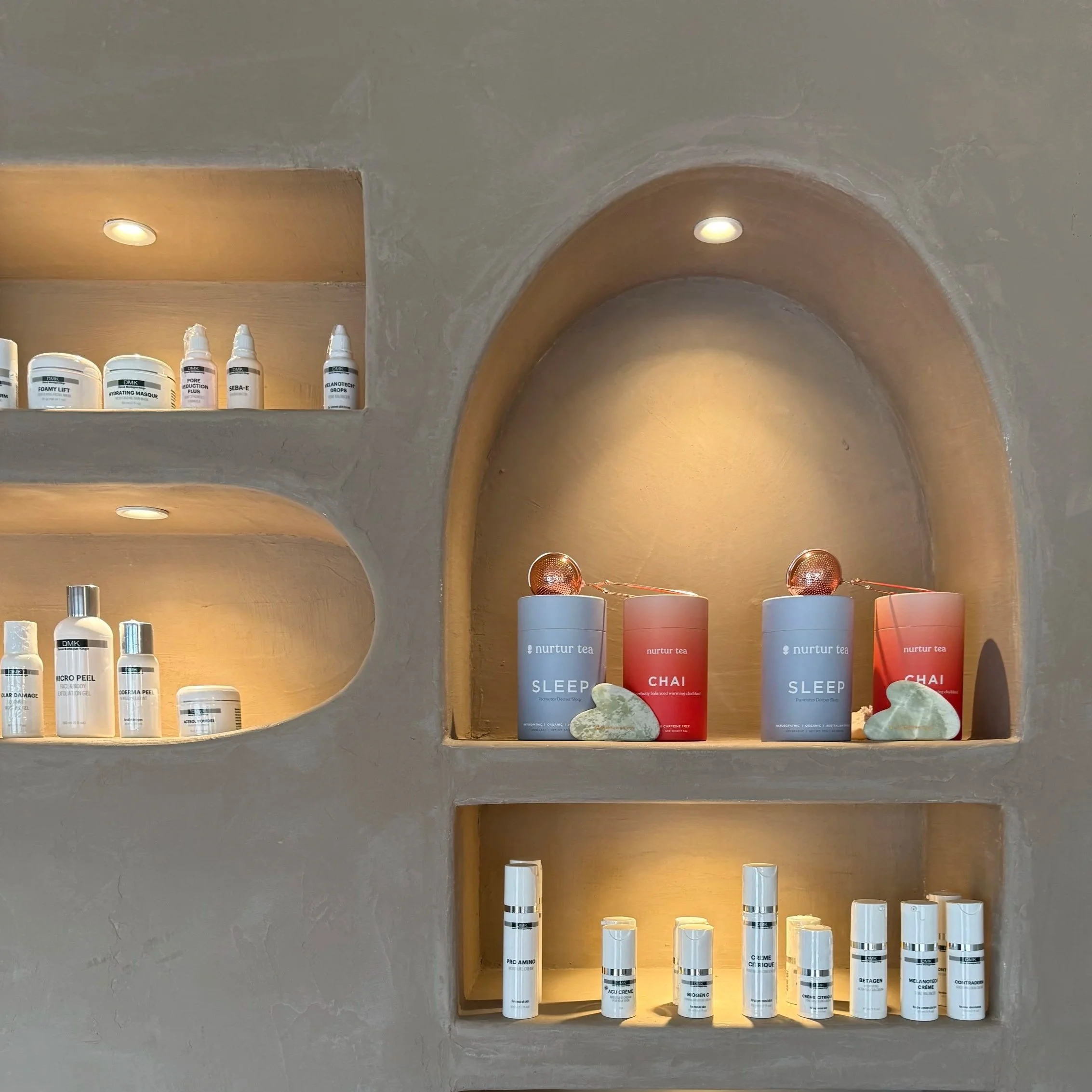 Shelves with skincare products and tea containers in a well-lit spa or wellness center.