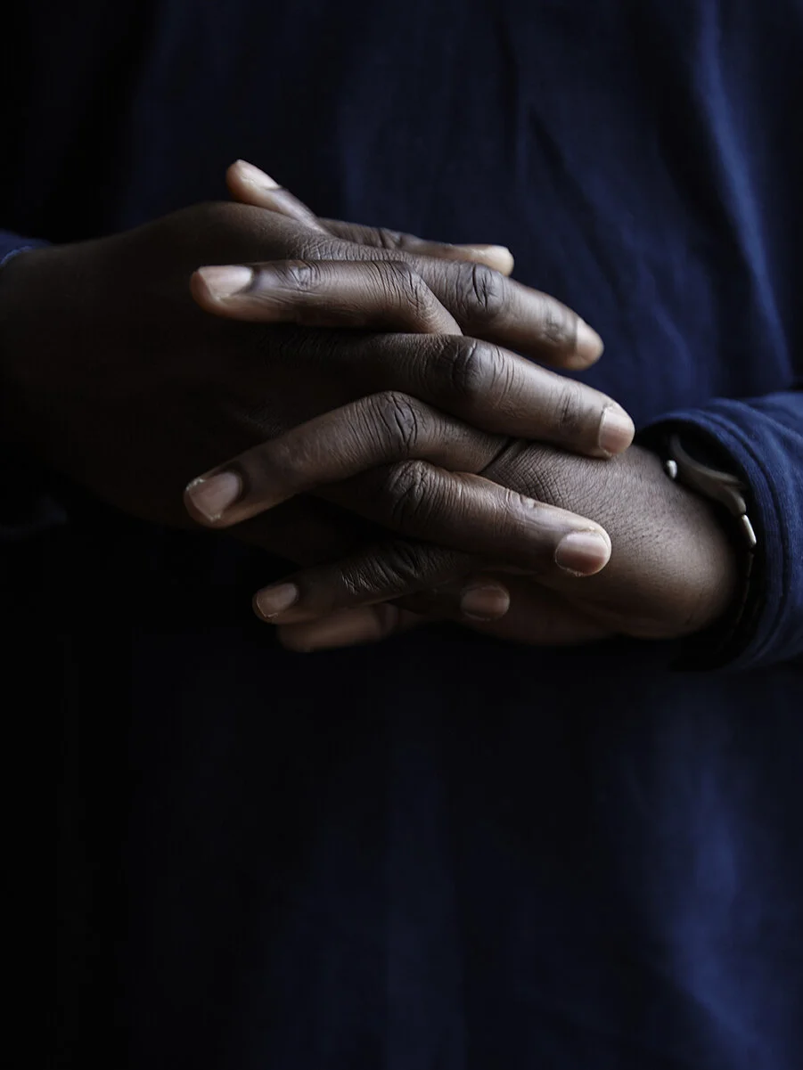 Verschränkte Hände auf dunklem Hintergrund.