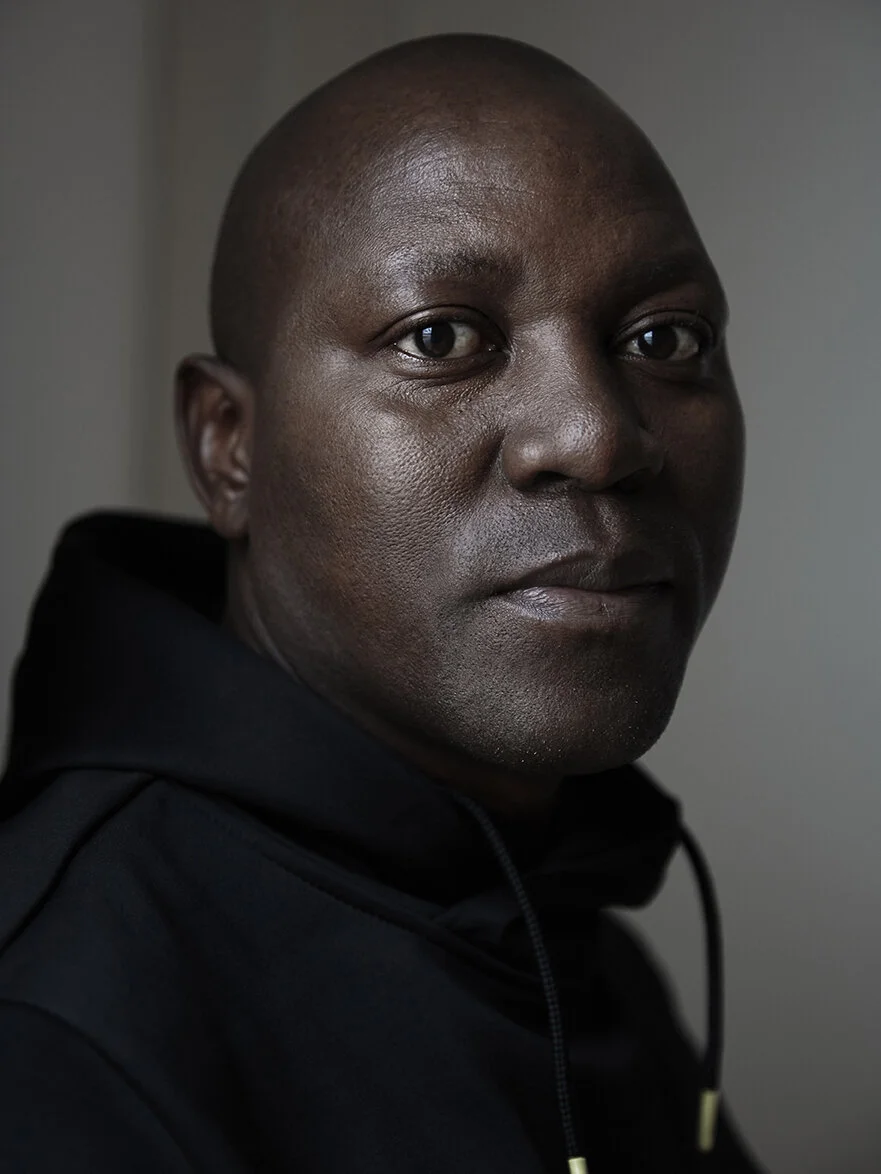 Porträt eines Mannes mit dunkler Hautfarbe in einem schwarzen Hoodie, neutraler Hintergrund. Nahaufnahme.