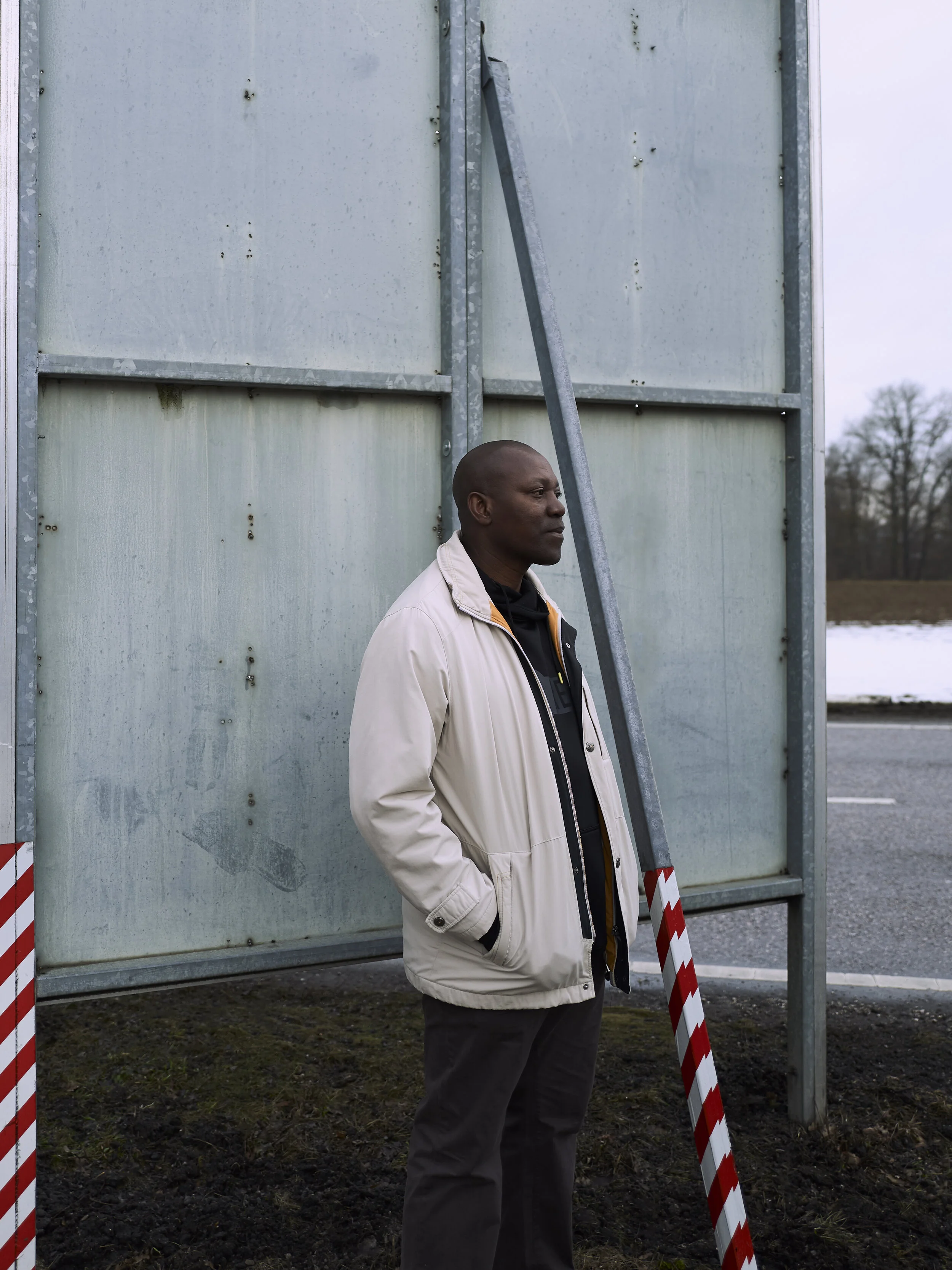Mann in heller Jacke steht neben einer Metallkonstruktion im Freien.