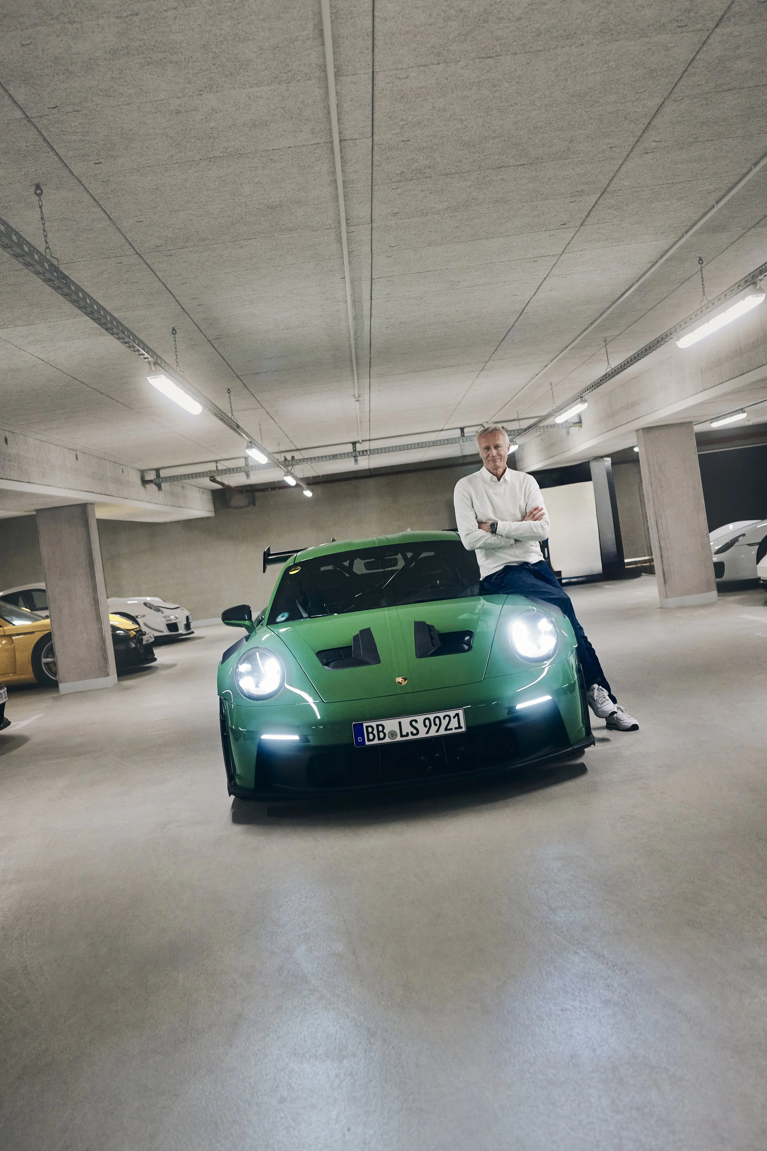 Person vor einem grünen Porsche in einer Tiefgarage