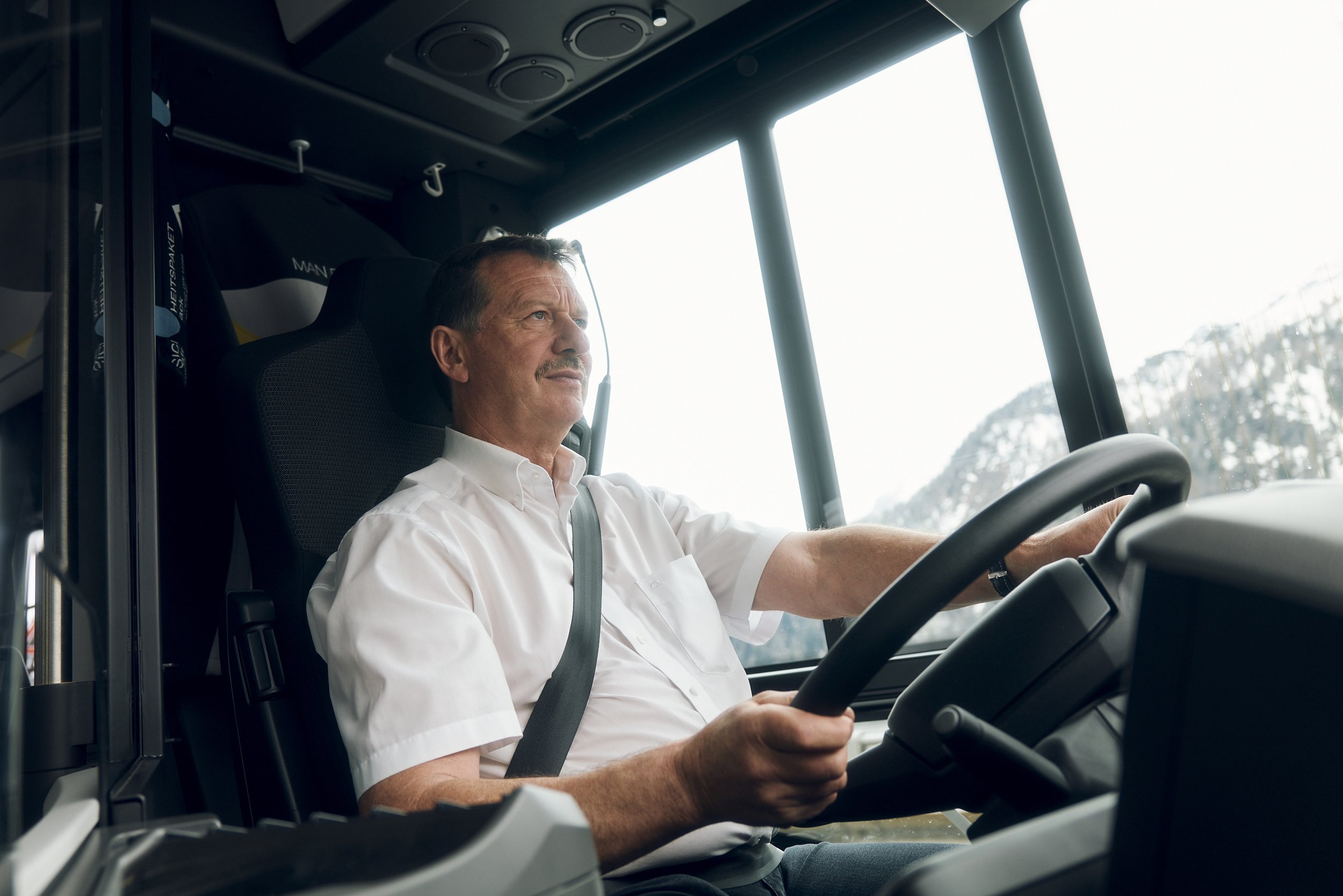 Mann in einem Bus, der am Steuer sitzt, mit Sicherheitsgurt.
