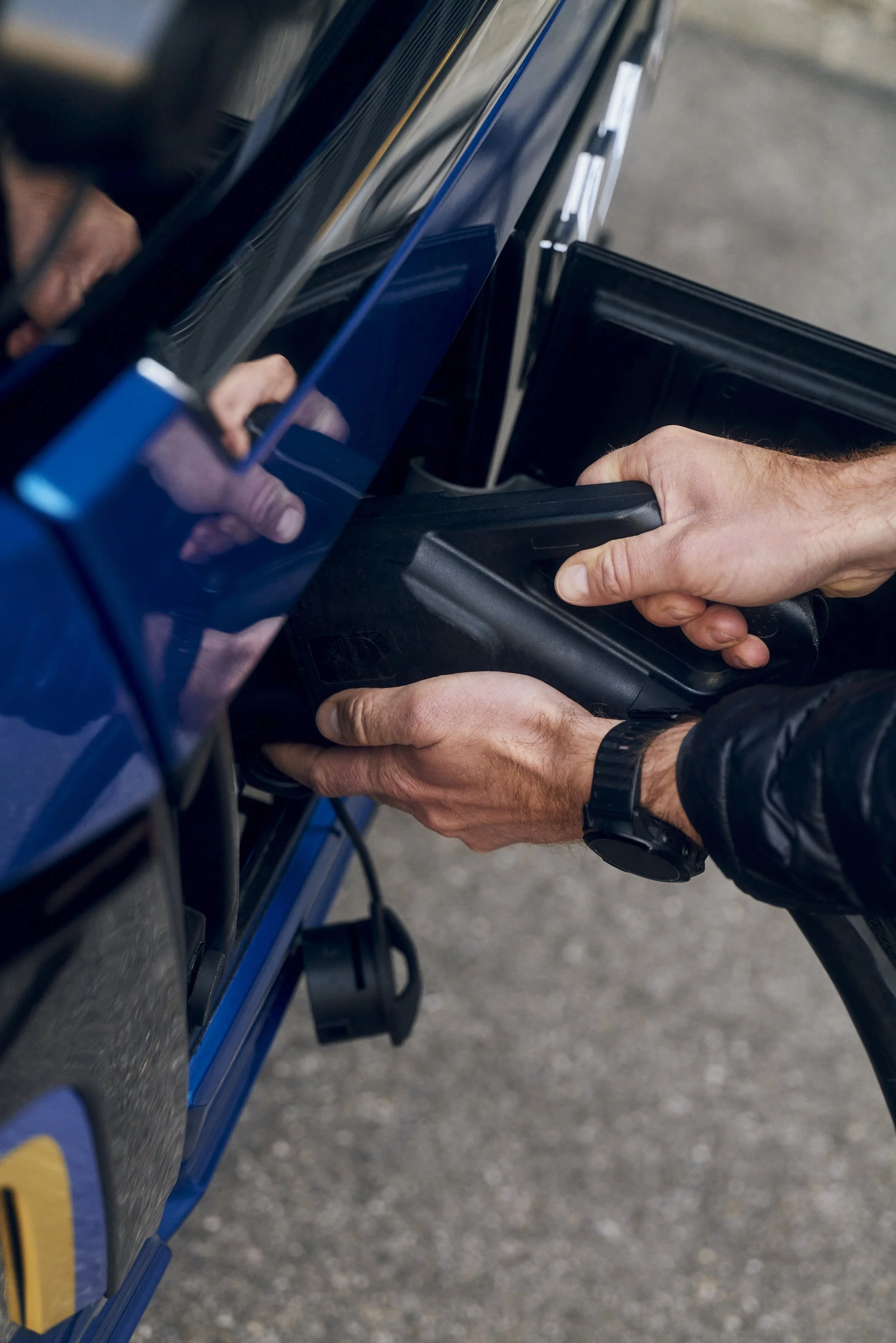 Eine Person lädt ein Elektroauto auf, indem sie das Ladekabel anschließt.