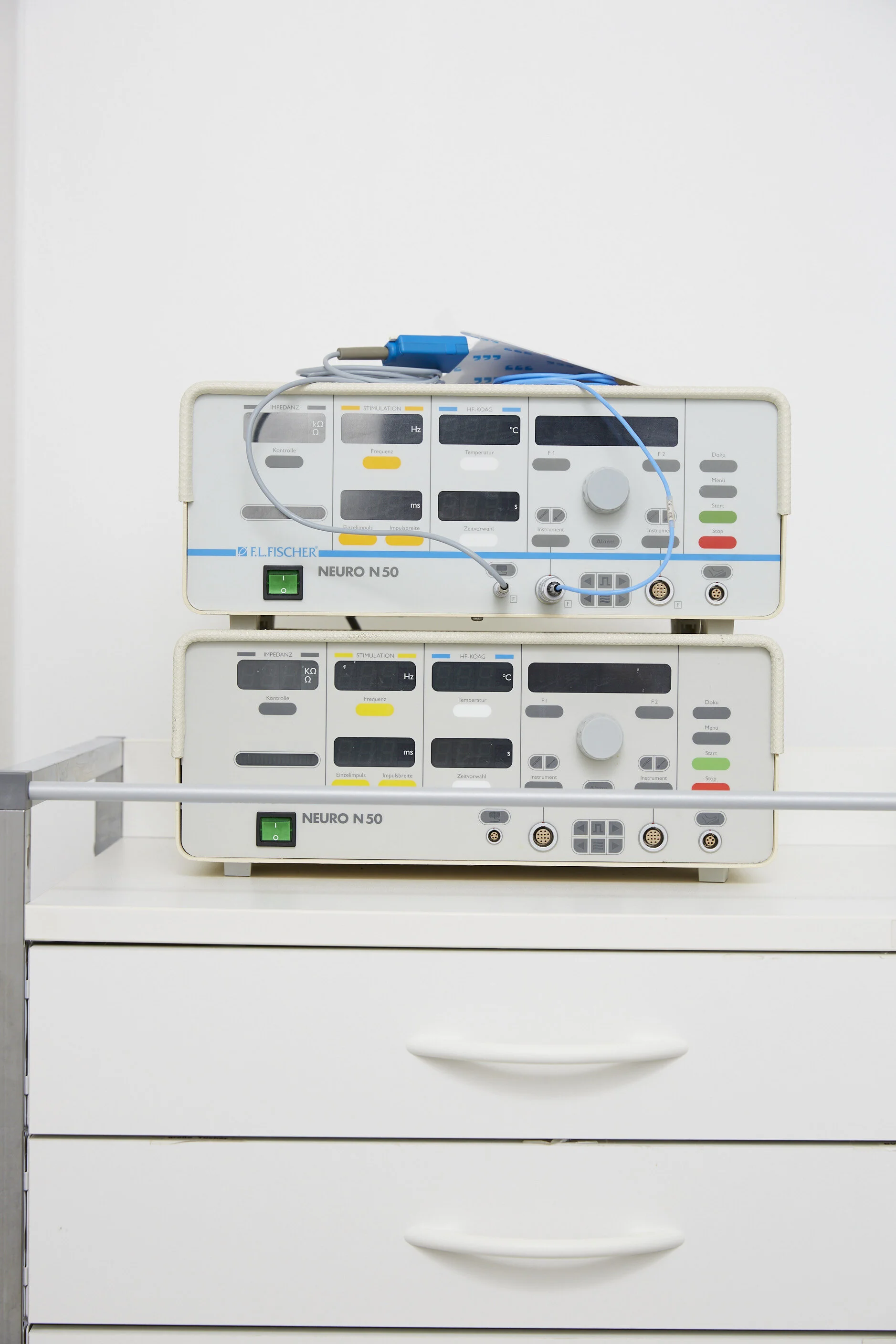 Mikroprozessor-gesteuerte Stimulationsgeräte der Marke Neuro N 50, übereinander gestapelt, auf einer weißen Schublade in einem medizinischen Umfeld.