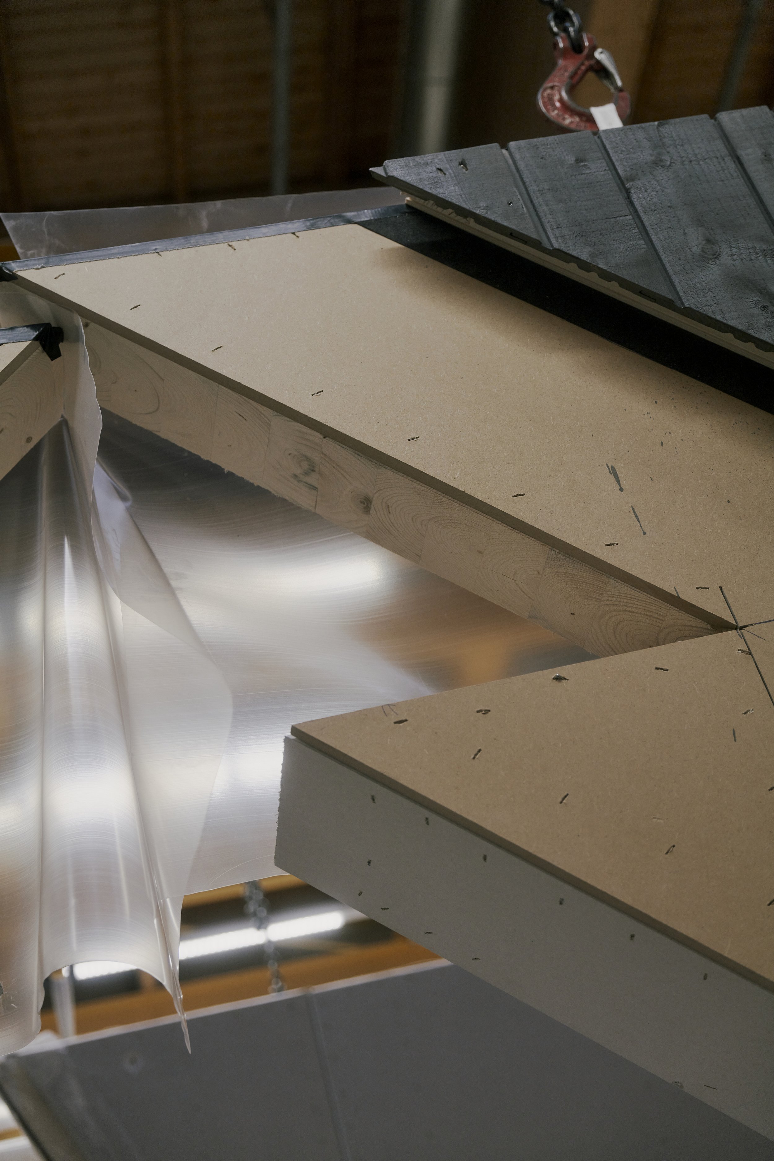 Bau einer Dachkonstruktion aus Holzplatten und Folie mit Haken.