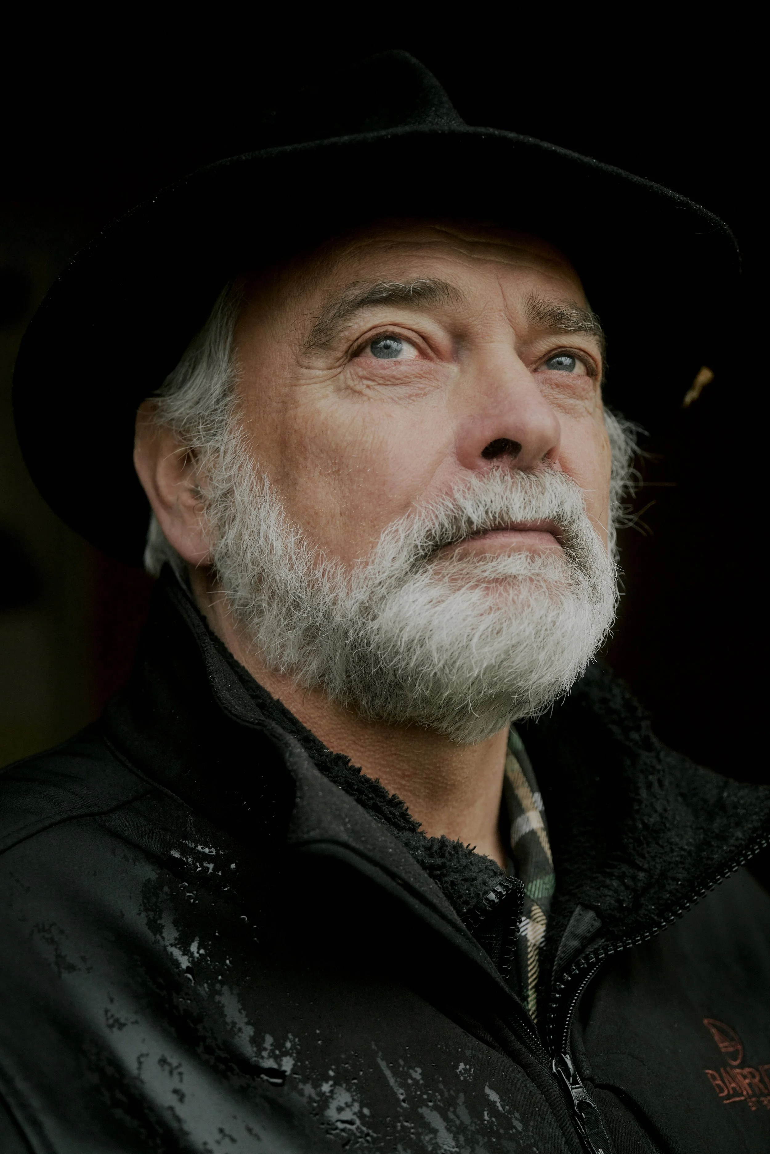 Porträt eines älteren Mannes mit Bart, der einen Hut und eine Jacke trägt.