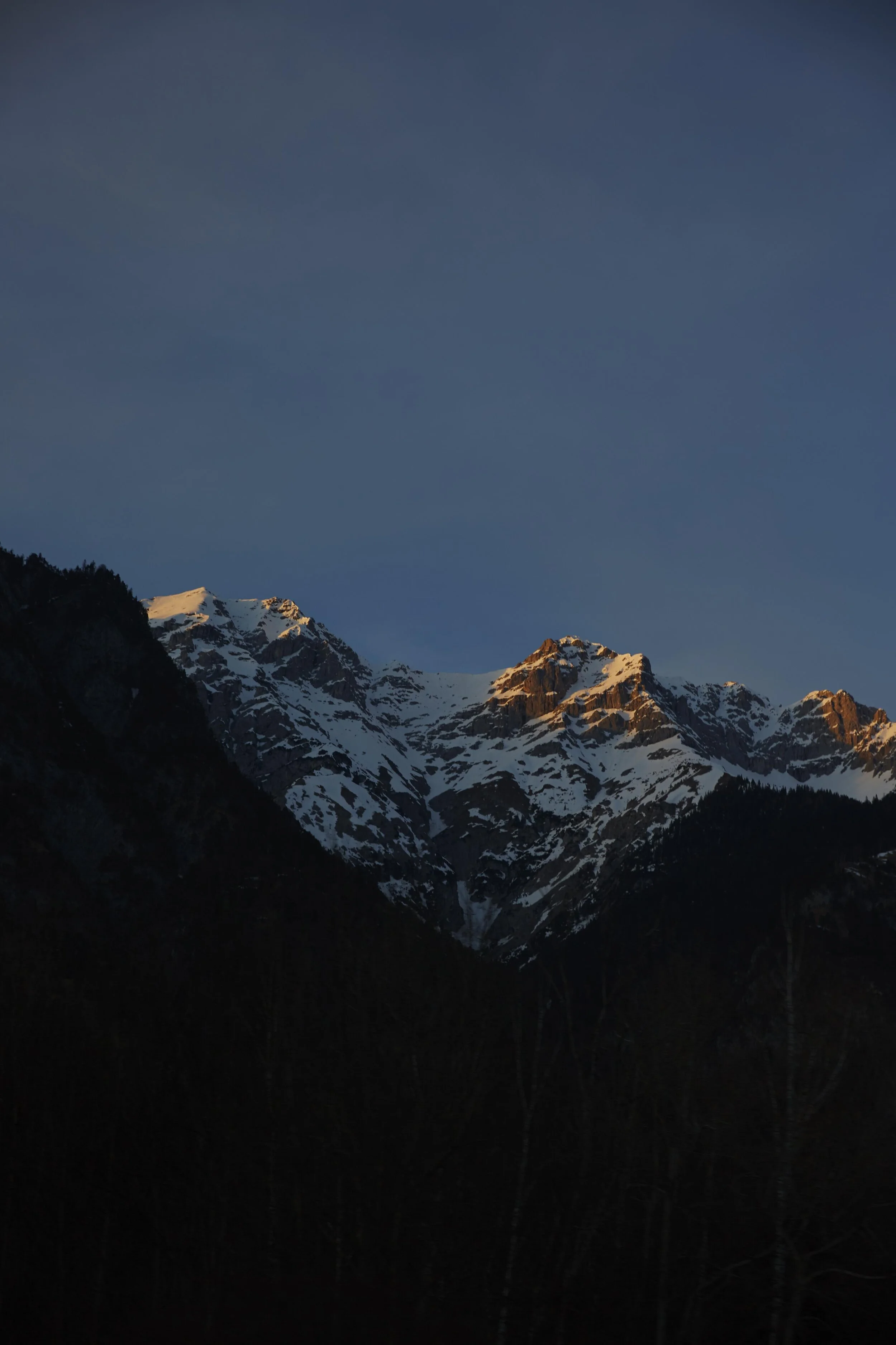 Am Ende des Rodeltages bescheint die untergehende Sonne schneebedeckte Bergspitzen.
