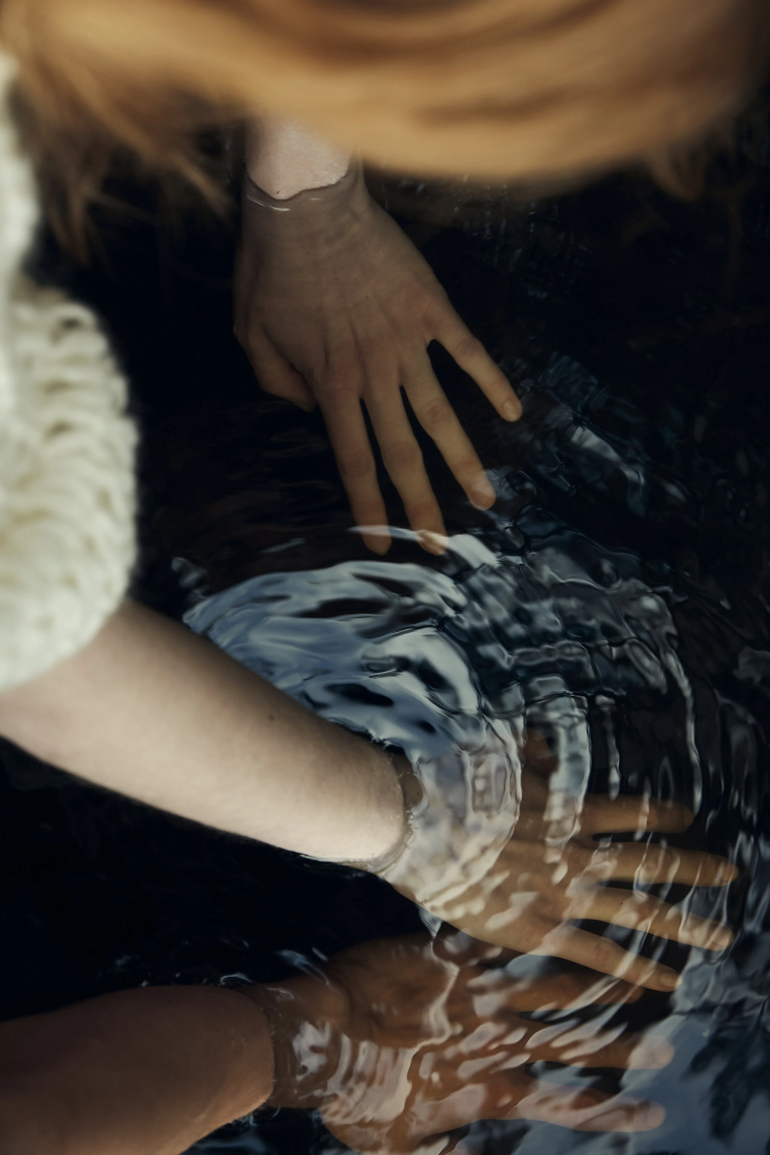 Zwei Hände, die im Wasser reflektiert werden.