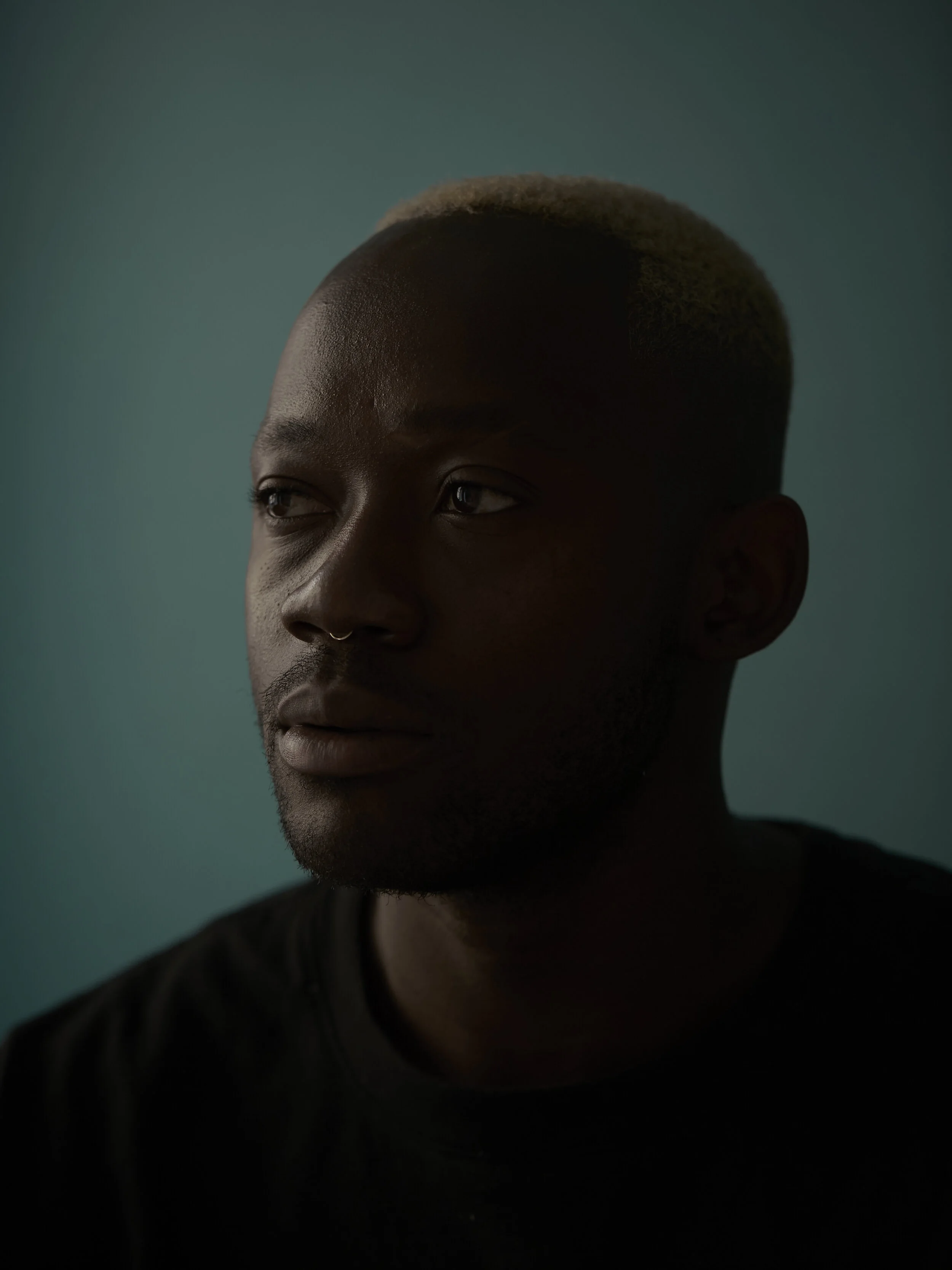 Porträt eines Mannes mit blondiertem Haar vor grauem Hintergrund.