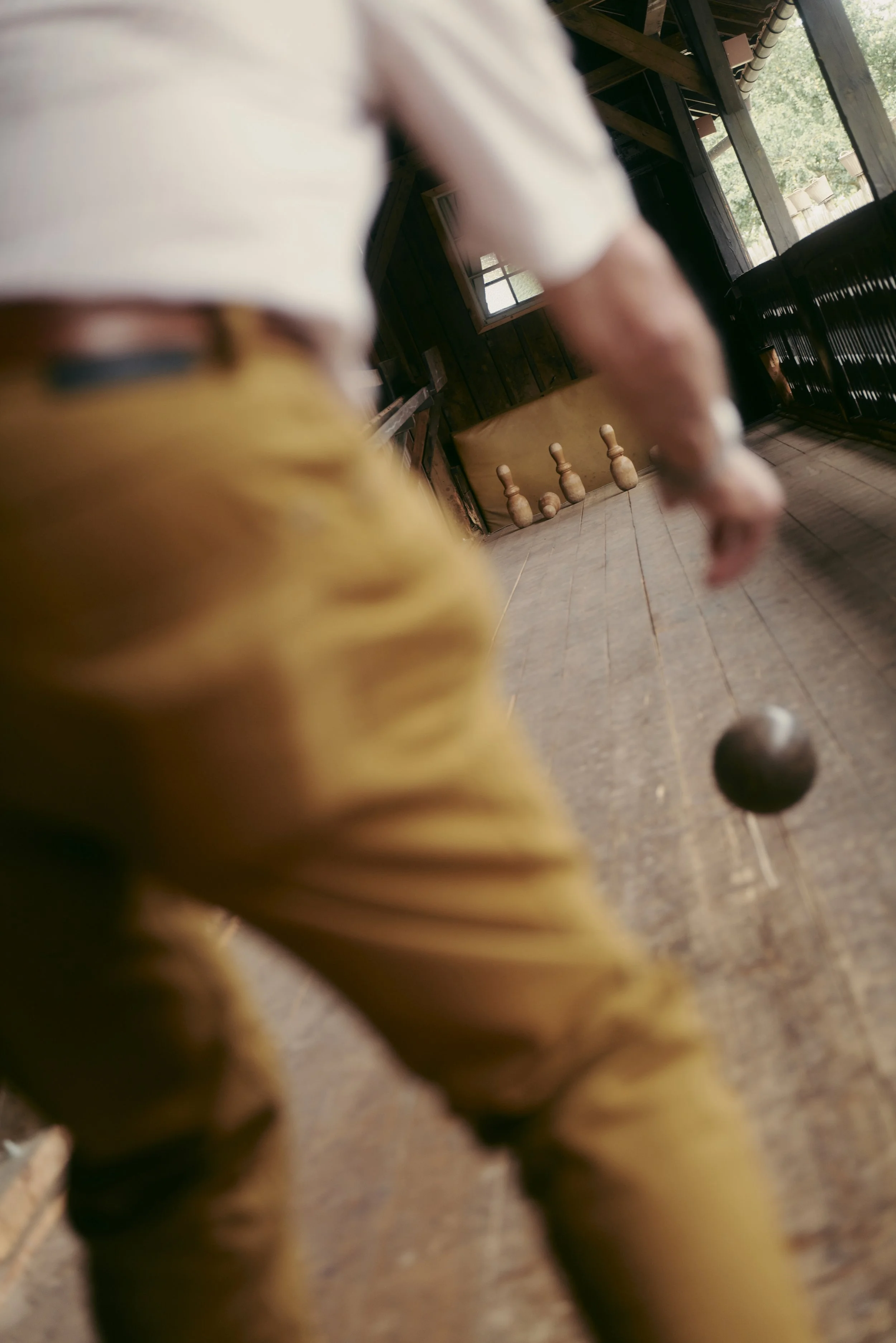 Person beim Kegeln, Kugel auf Bahn in Richtung Kegel