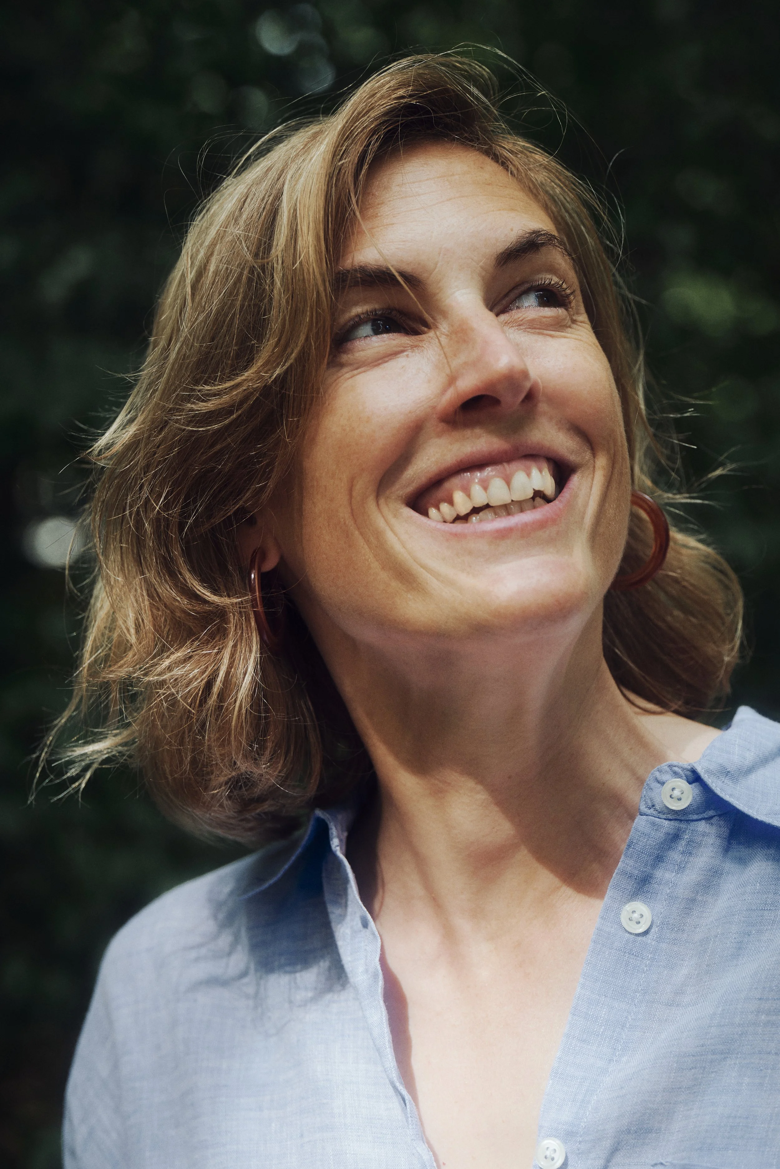 Isabelle Rickmers mit kurzen, welligen Haaren und einem hellblauen Hemd vor unscharfem, grünem Hintergrund