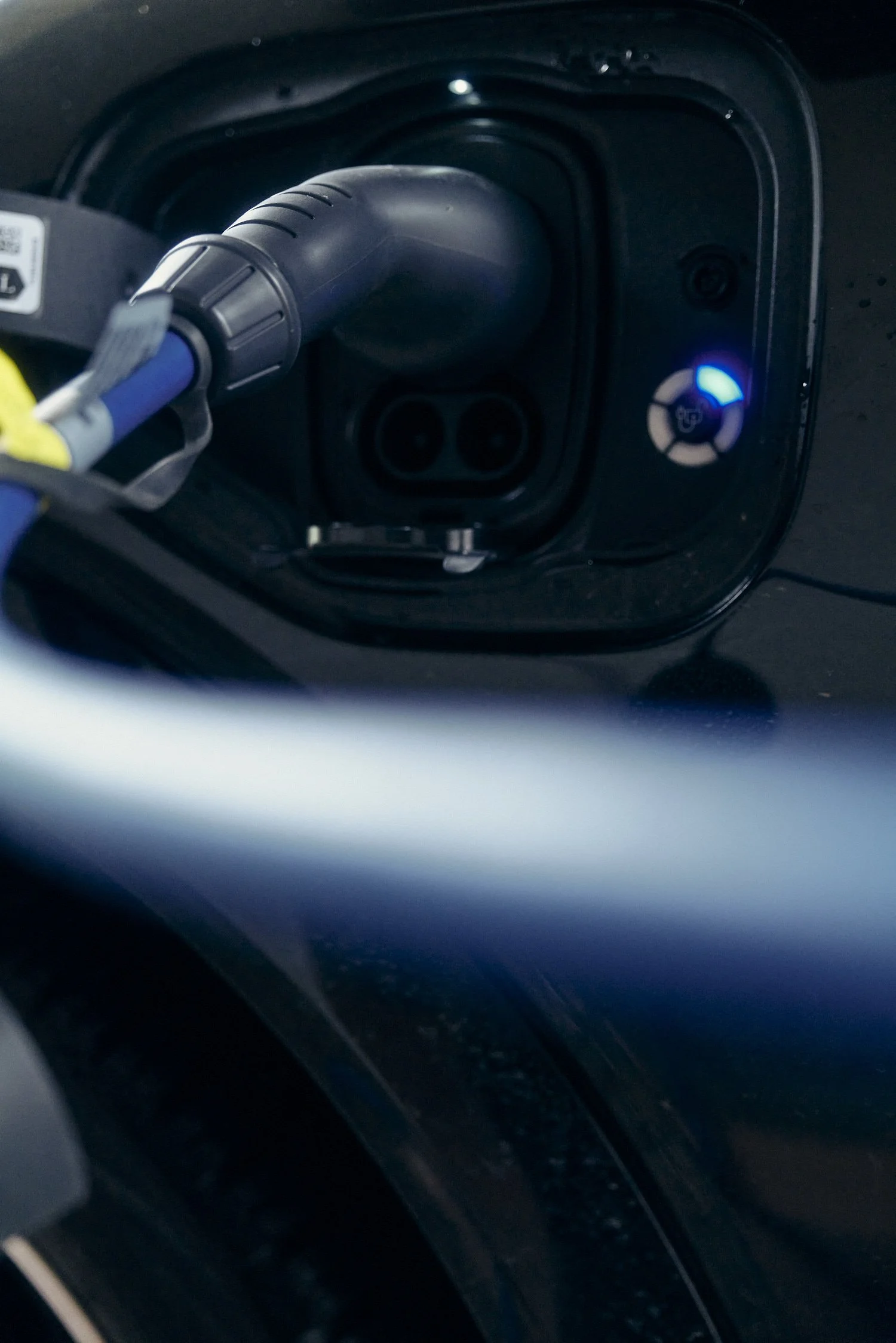 Nahaufnahme eines Elektroauto-Ladeanschlusses mit angestecktem Ladekabel