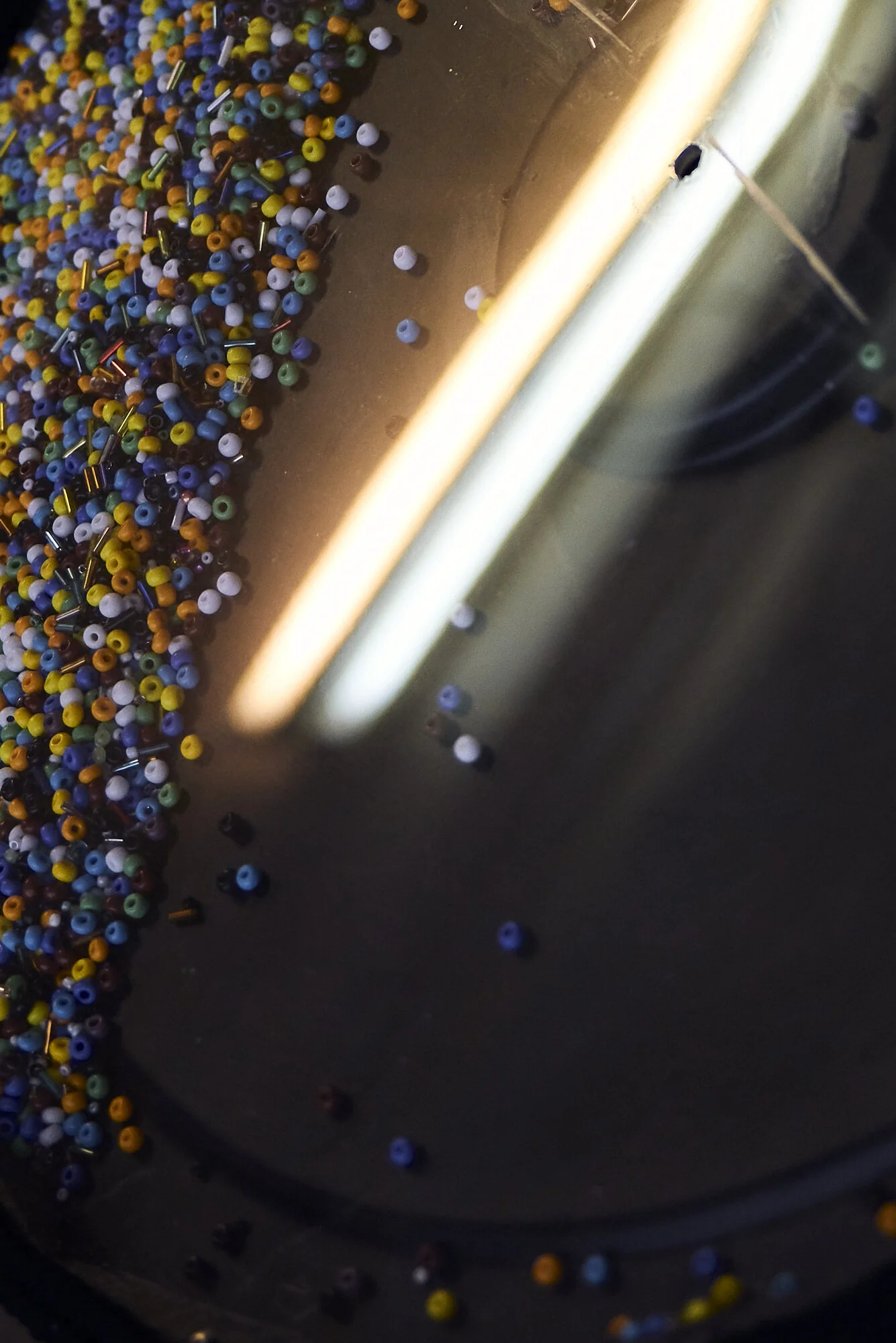 Nahaufnahme von vielen bunten kleinen Perlen auf einer flachen Oberfläche.