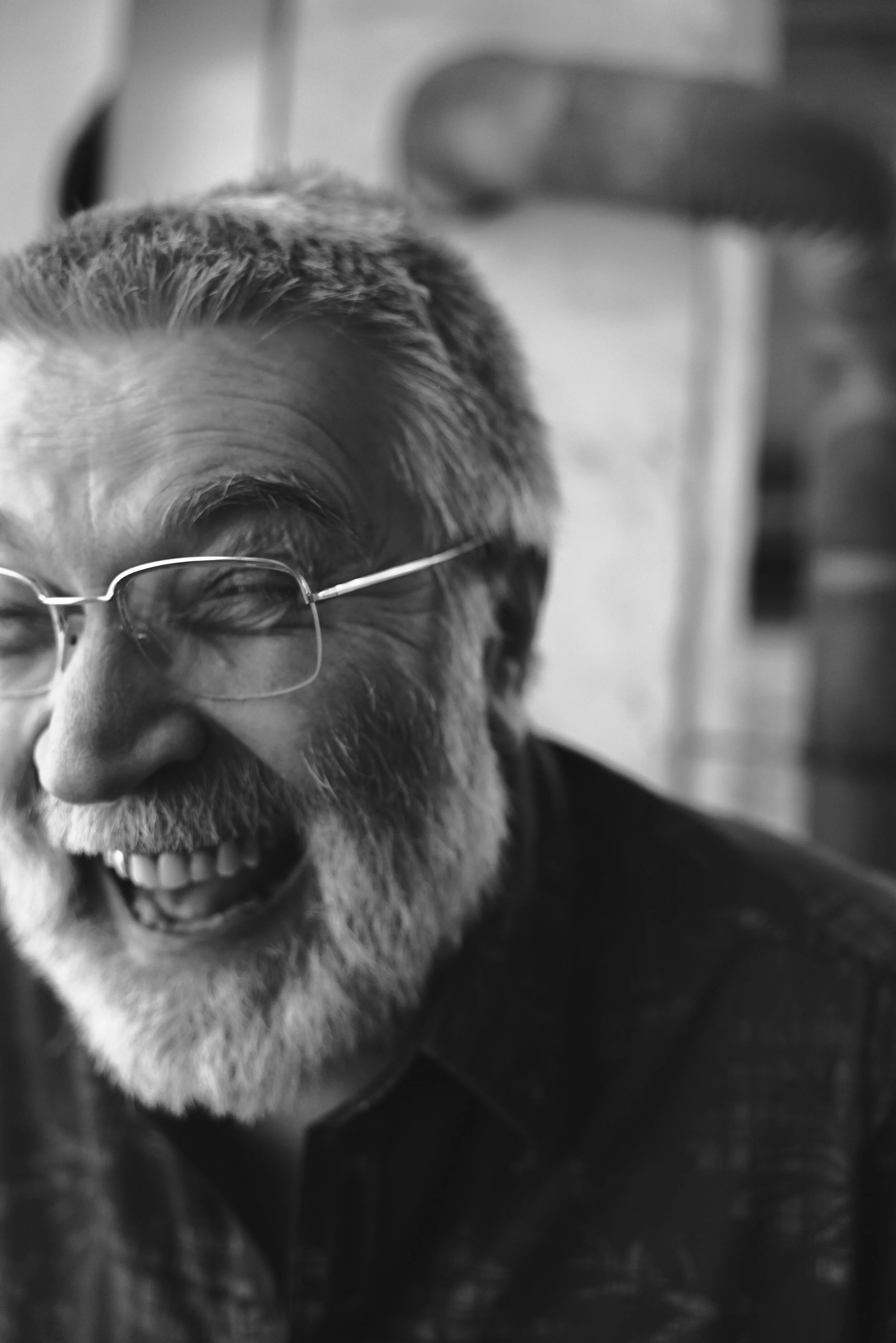 Ein älterer Mann mit Brille und Bart lacht herzlich.