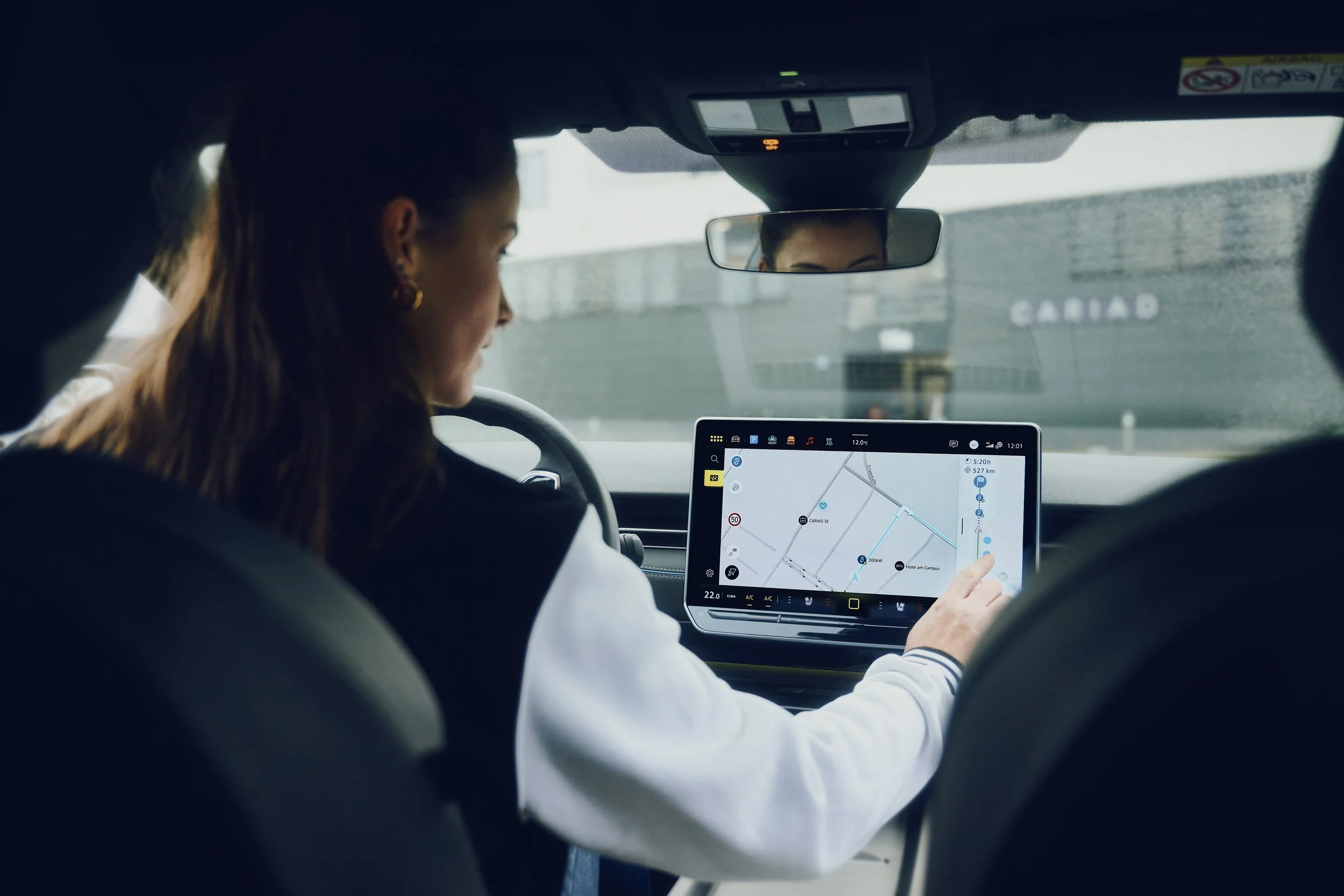 Frau im Auto benutzt Navi auf großem Bildschirm.