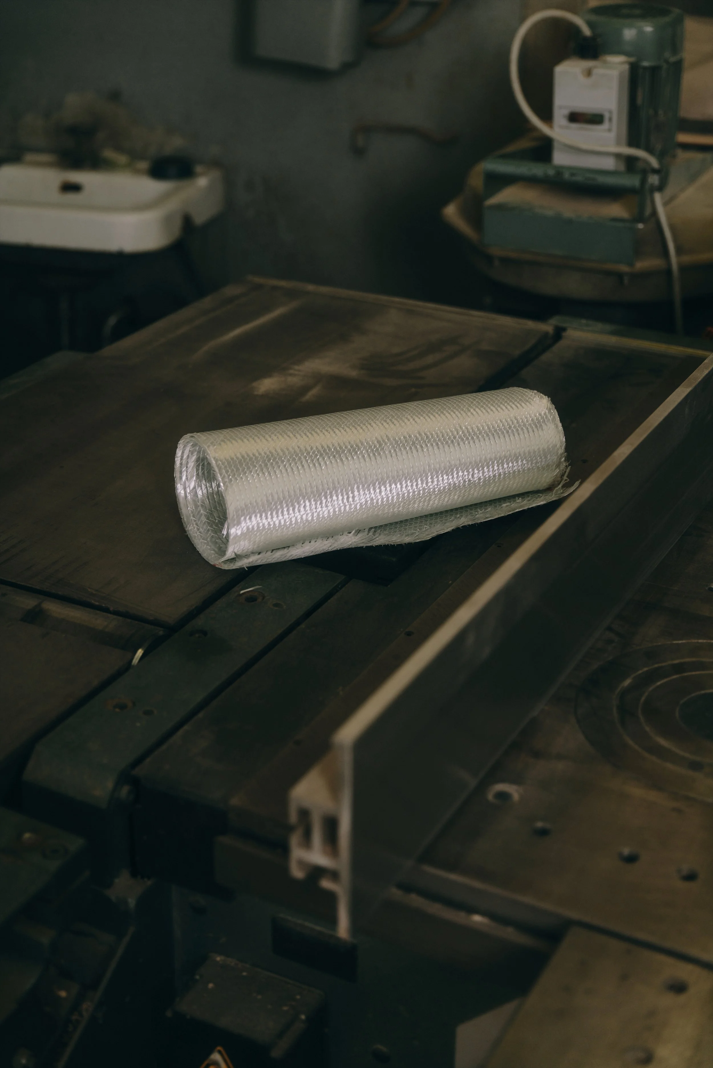 Rolle aus Fiberglasgewebe auf einer Metallwerkbank in einer Werkstatt.