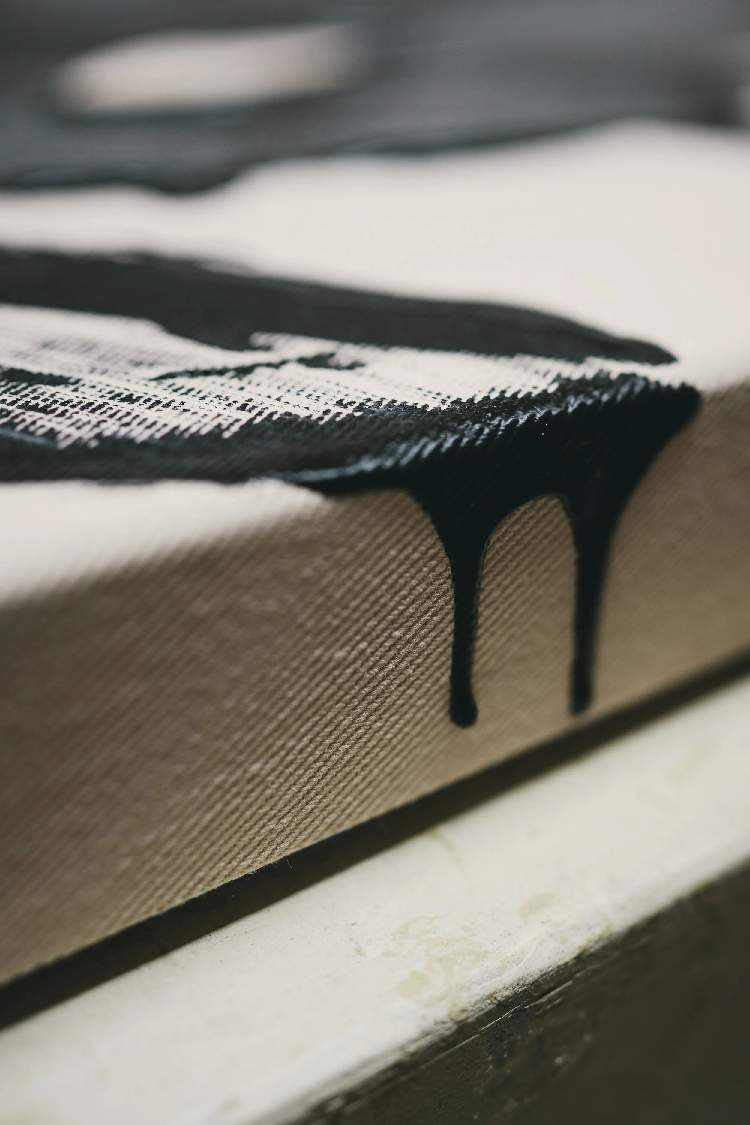 Nahaufnahme einer Leinwand mit schwarzer Farbe, die über den Rand fließt.