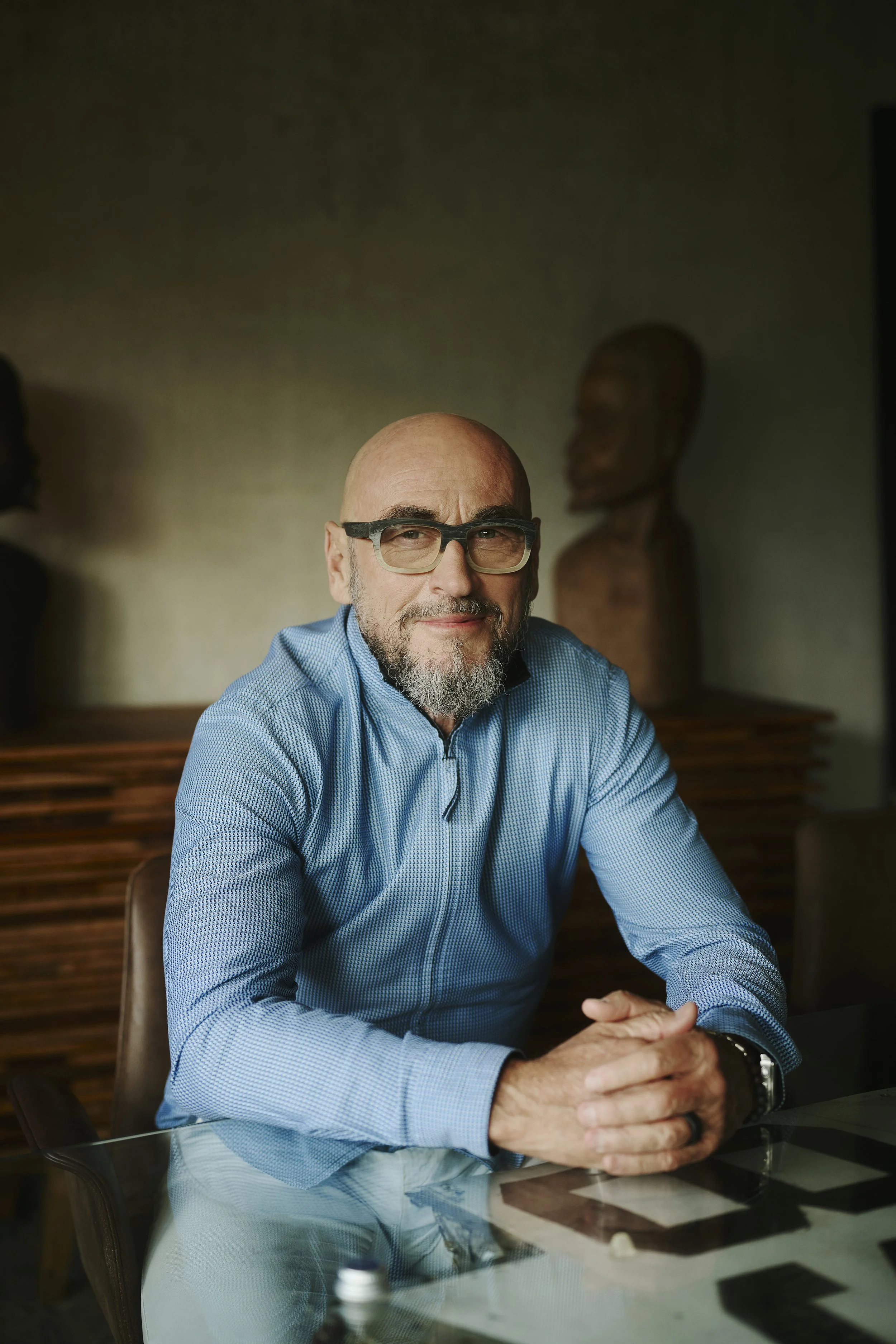 Jochen Schweizer sitzt an einem Tisch, trägt ein hellblaues Hemd.