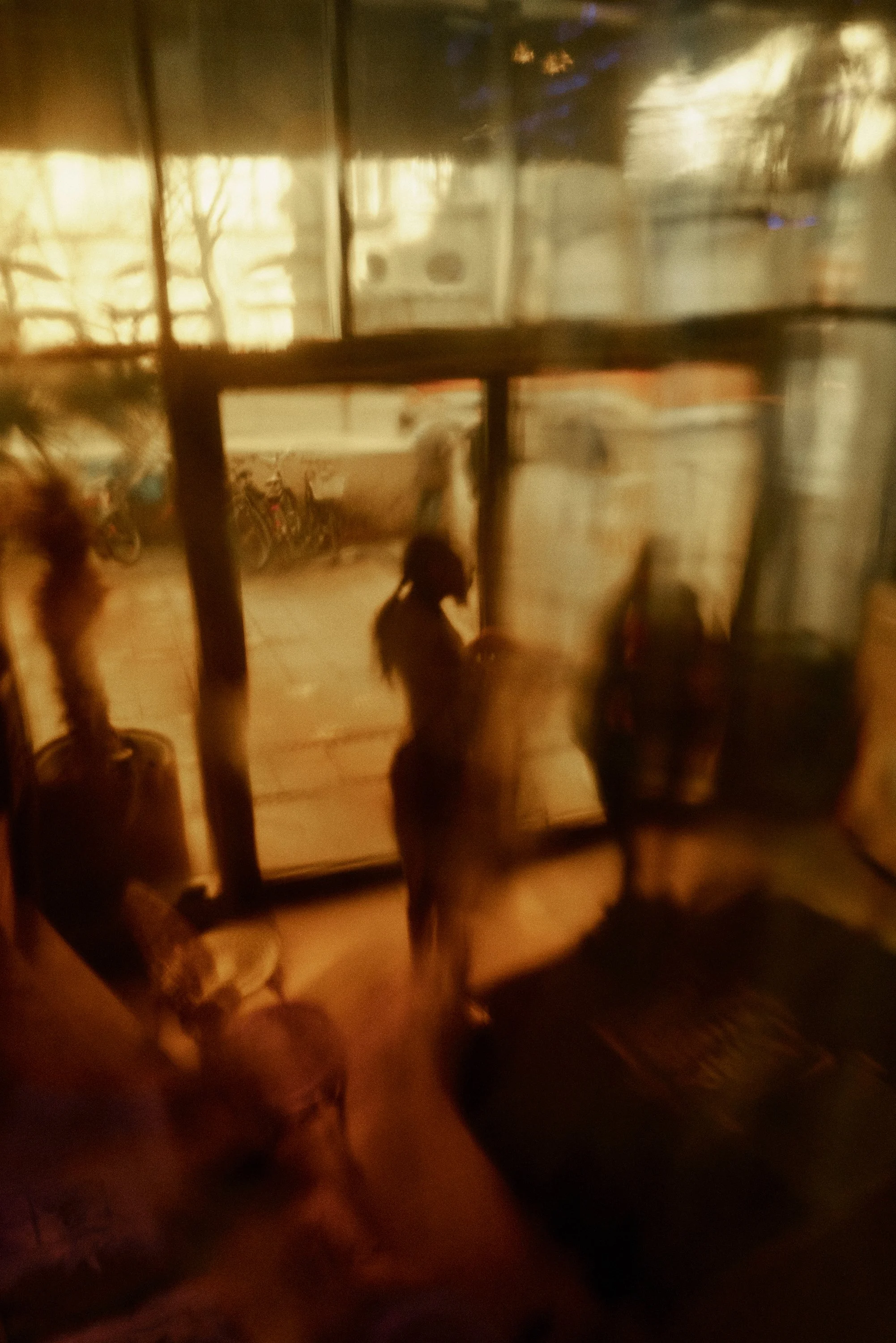 Unschärfe Foto von Menschen und Fahrrädern hinter einem Fenster.