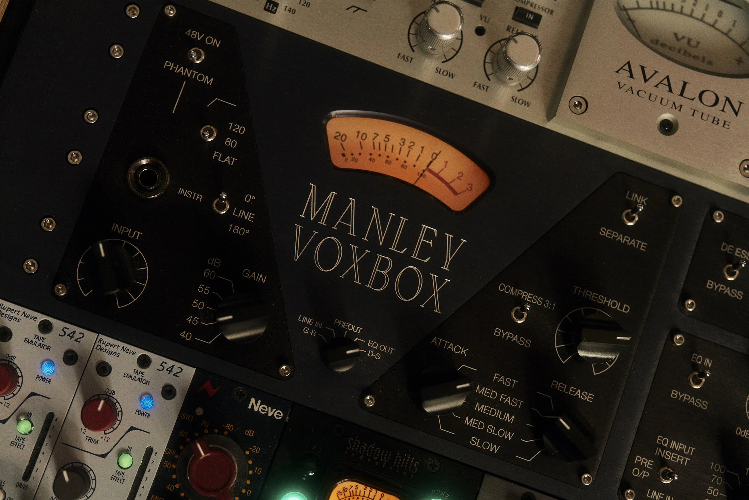 Manley Voxbox, ein hochwertiger Audio-Prozessor mit Reglern für Gain, Kompression und EQ, umgeben von anderen Audio-Ausrüstungen.