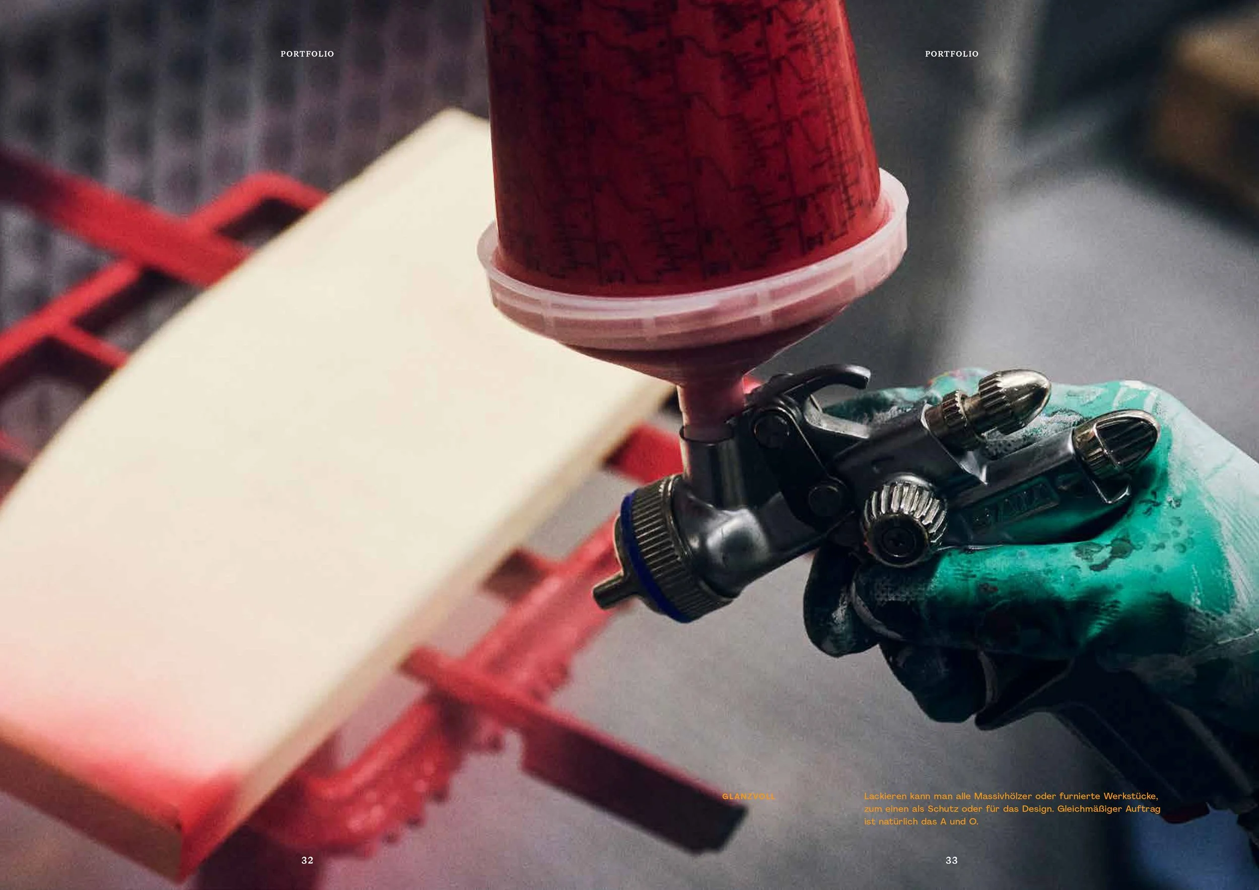 Hand mit Handschuh hält eine Spritzpistole, die rote Farbe auf ein Objekt sprüht.