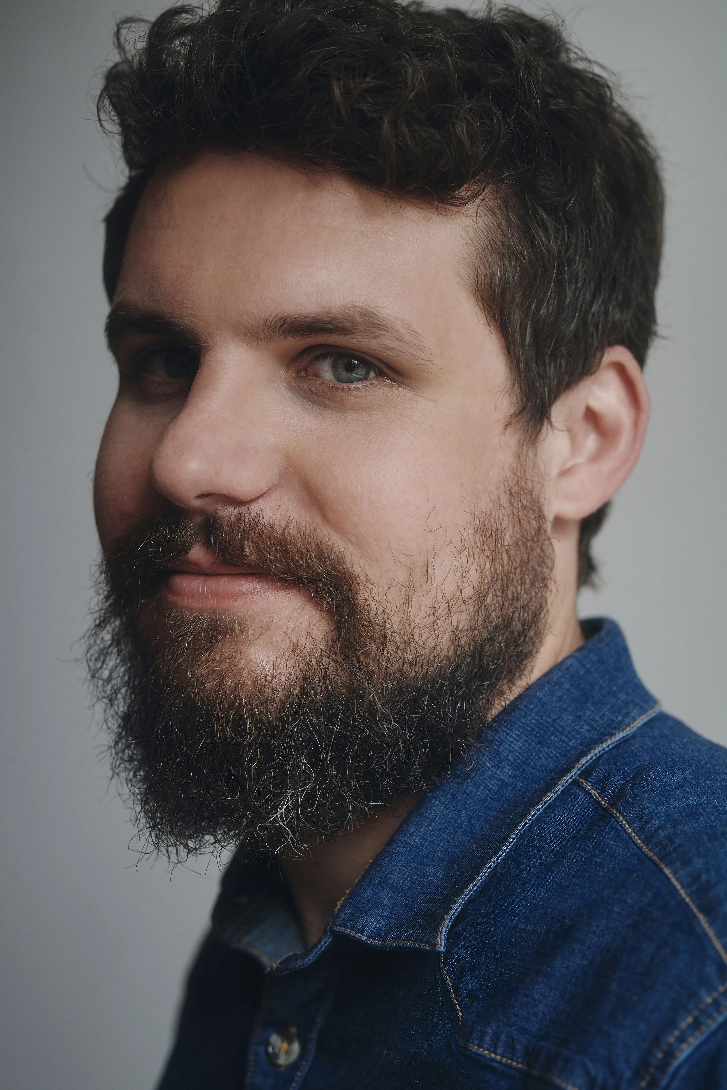 Porträt eines Mannes mit Bart und Jeanshemd.