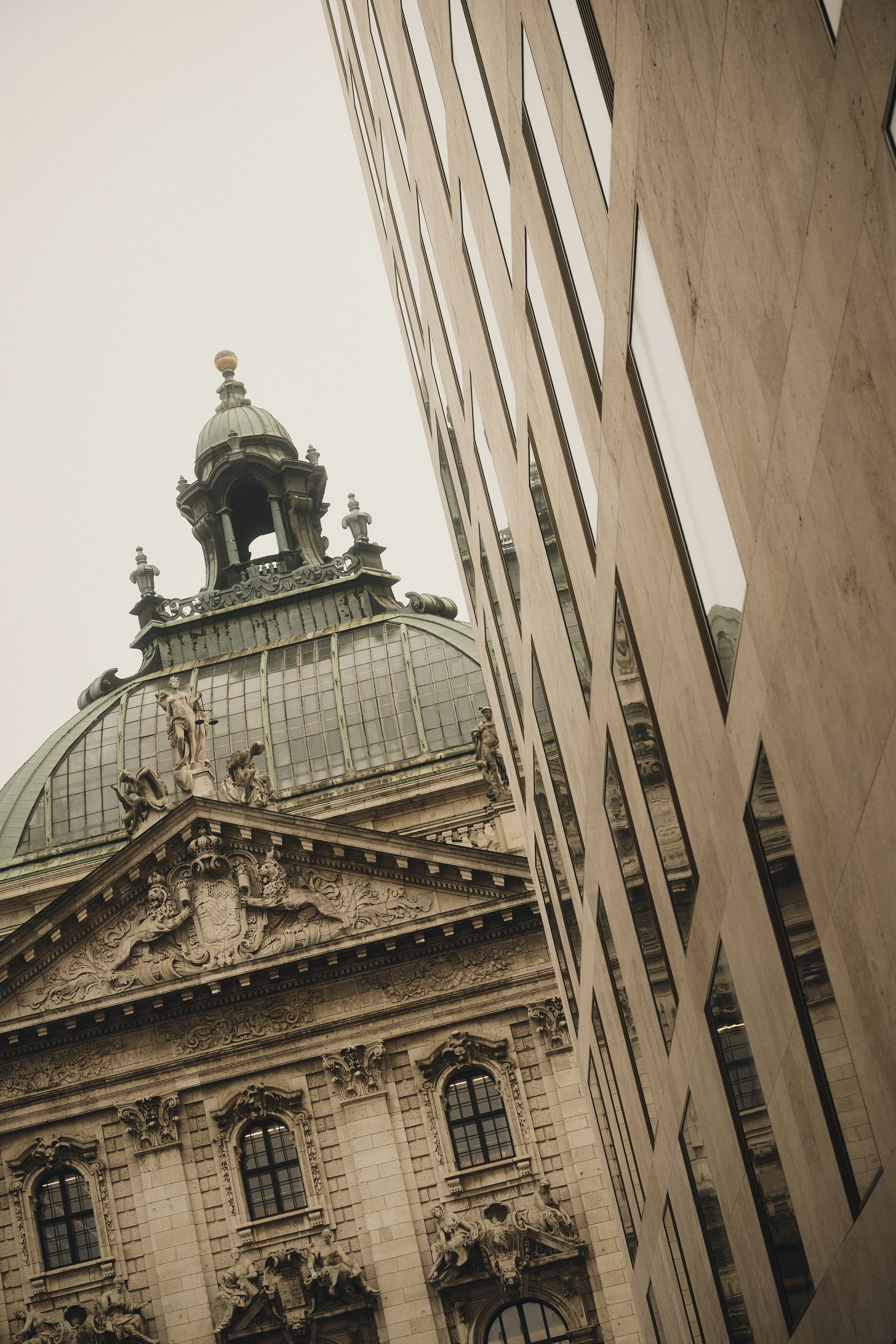 Historisches Gebäude mit Kuppel und Verzierungen neben einem modernen Hochhaus in der Stadt.