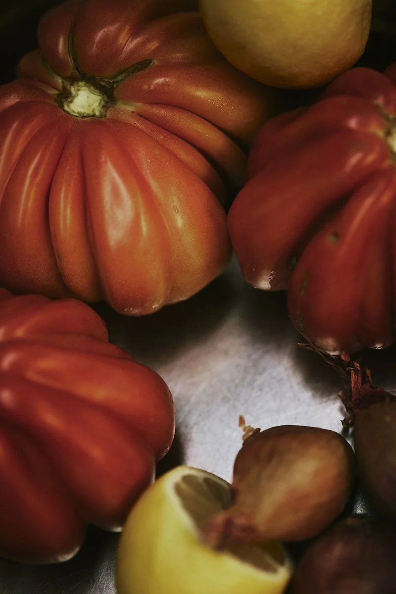 Tomaten, Zwiebeln und eine halbe Zitrone auf einer Metalloberfläche.