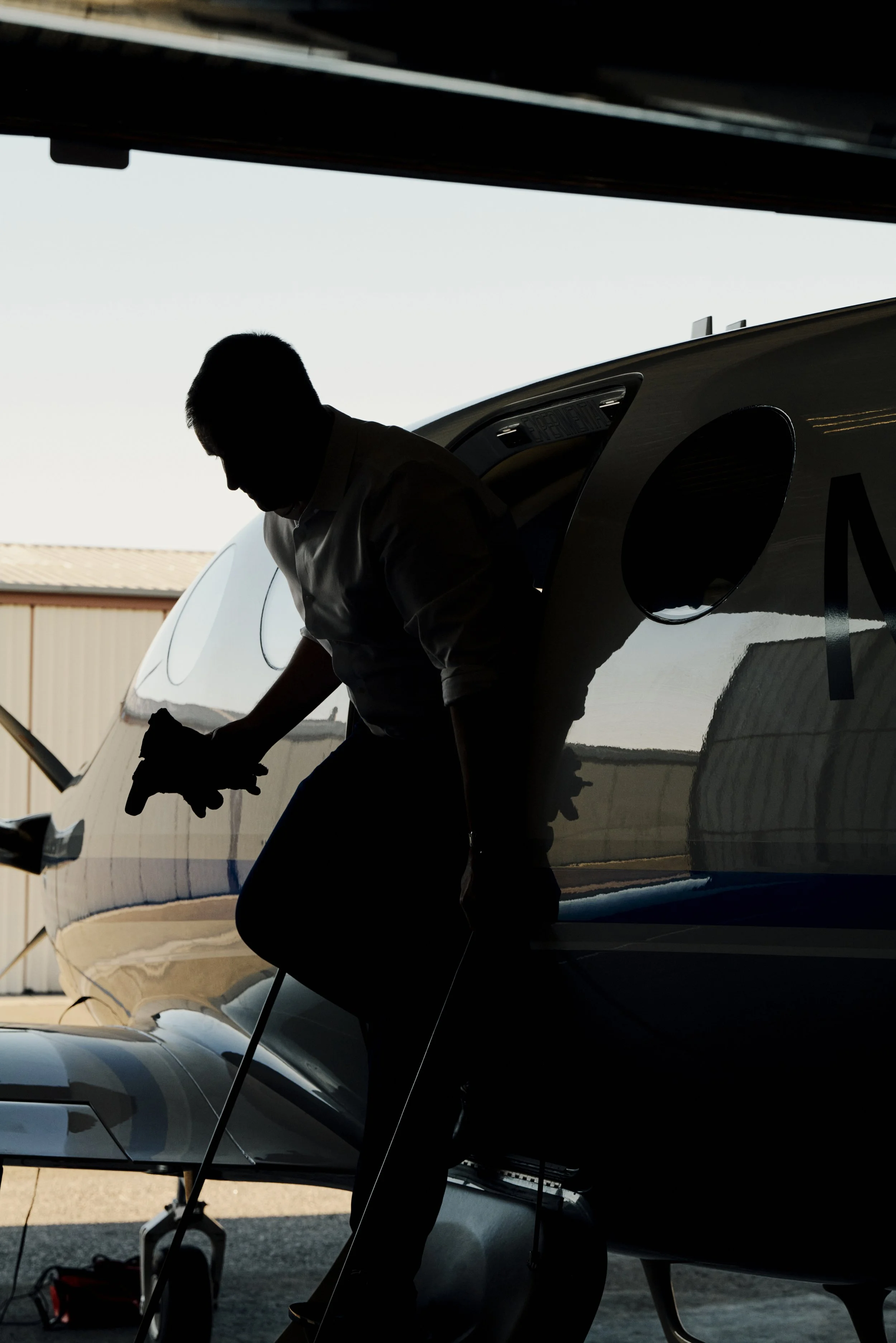 Silhouette einer Person, die aus einem Flugzeug steigt, vor hellem Hintergrund.