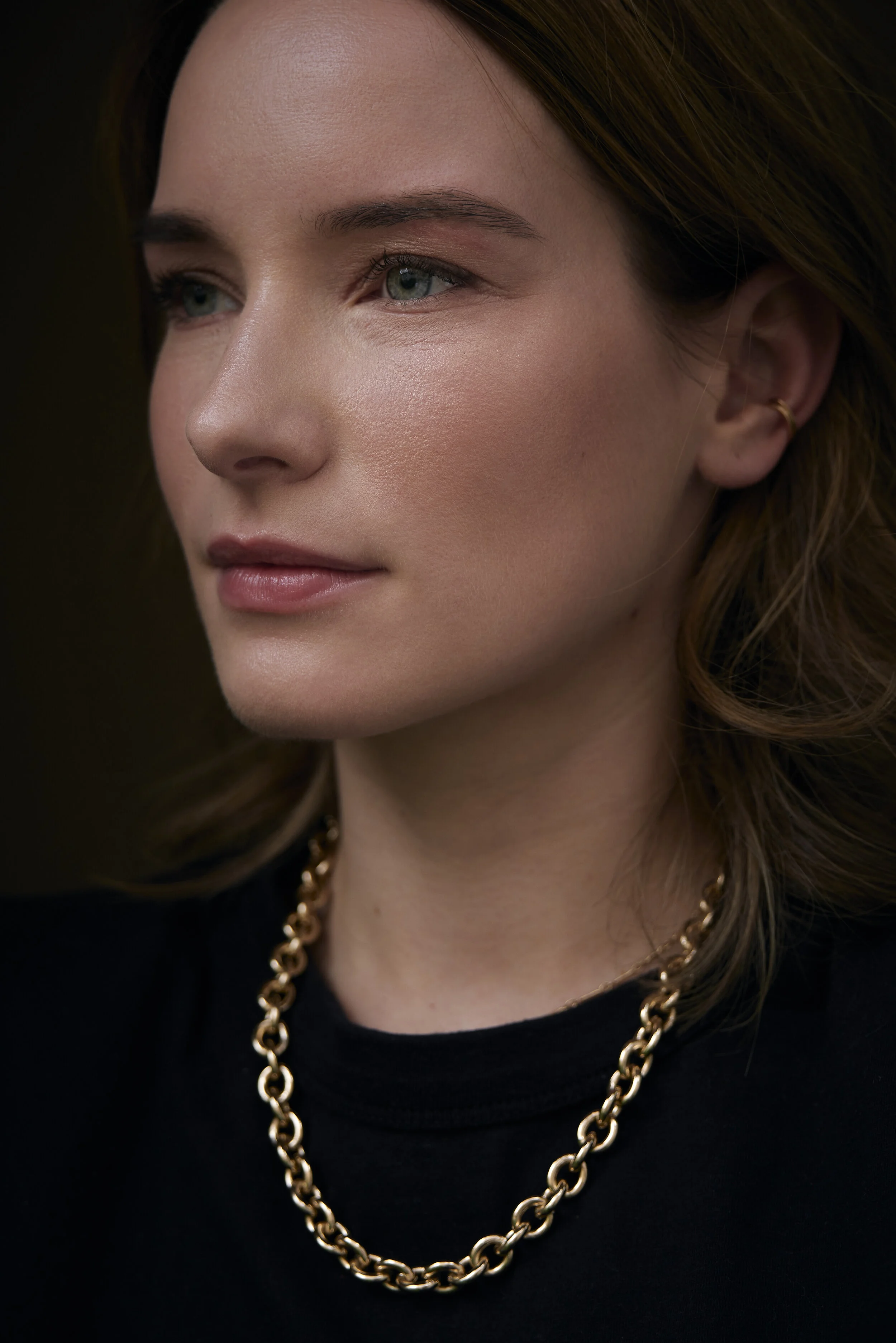 Nahaufnahme einer Frau mit einer goldenen Kette und schwarzen Kleidung.
