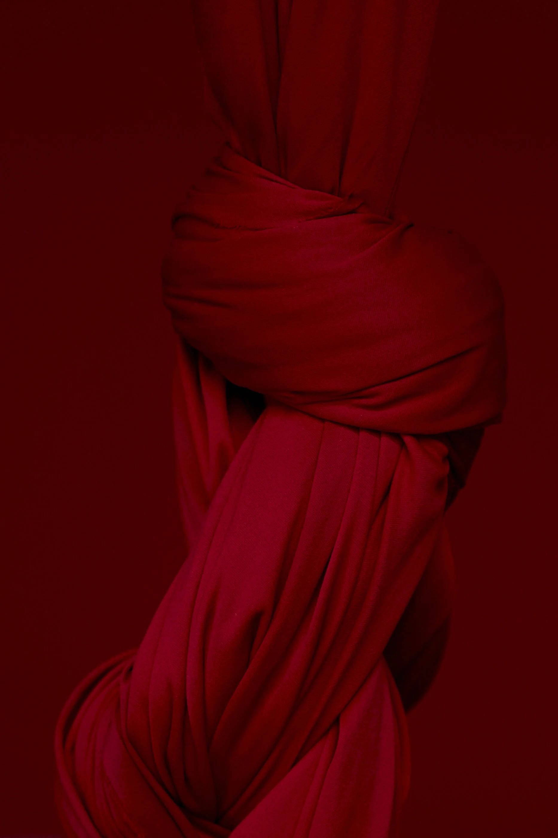 Nahaufnahme eines geknoteten roten Stoffes vor rotem Hintergrund.