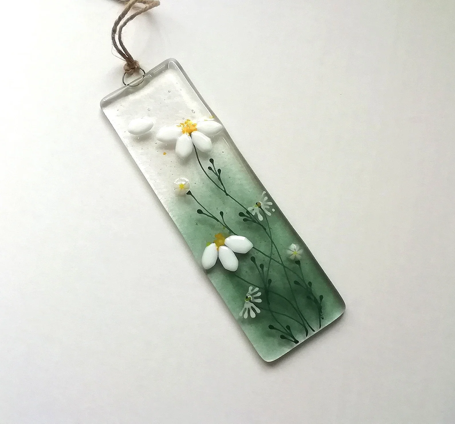 Decorative glass piece with painted white and yellow daisies, attached to a string collar.