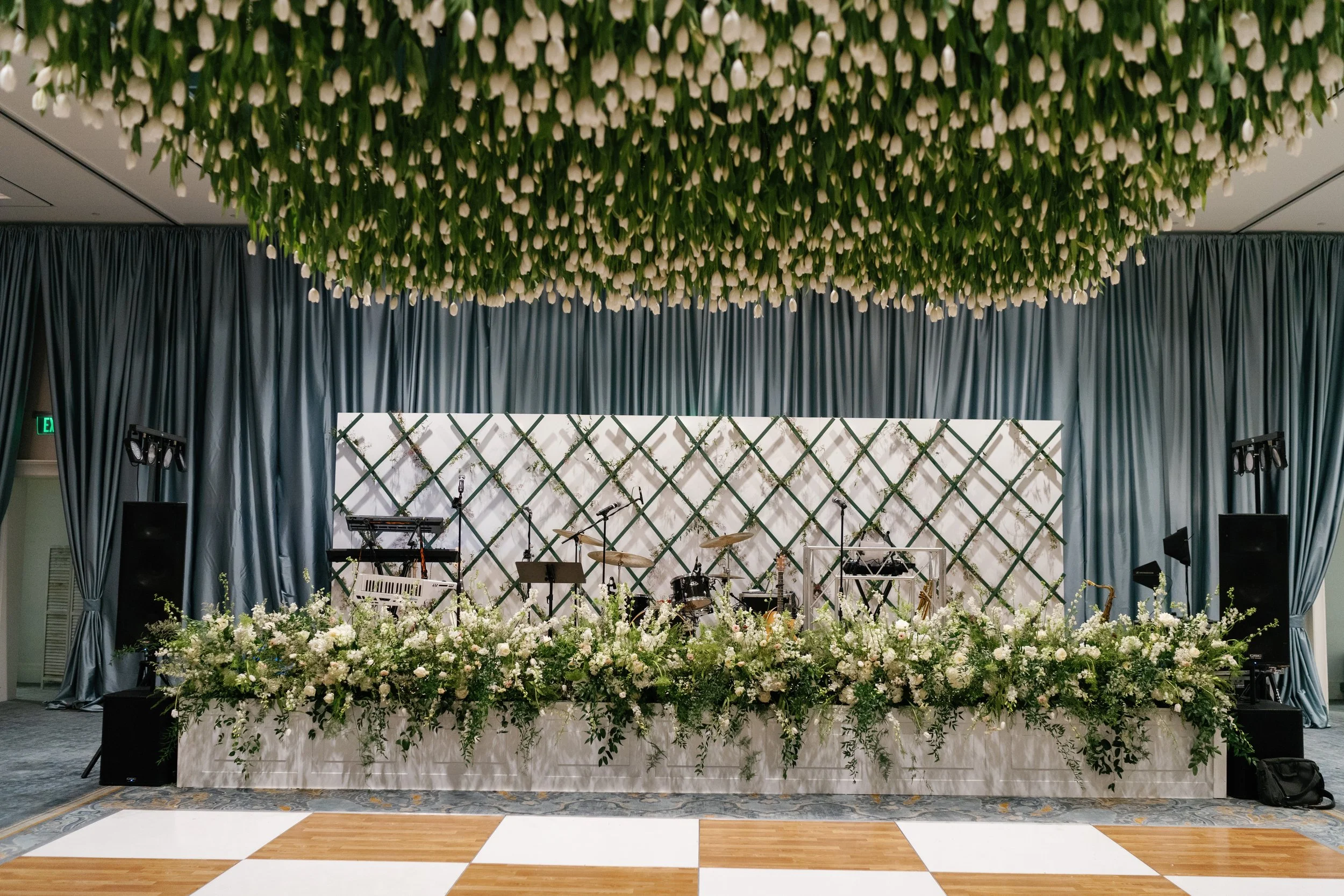 Wedding Reception featuring a canopy of fresh tulips. Thousands of white tulips hang above the dance floor while a stunning floral display adorns the stage