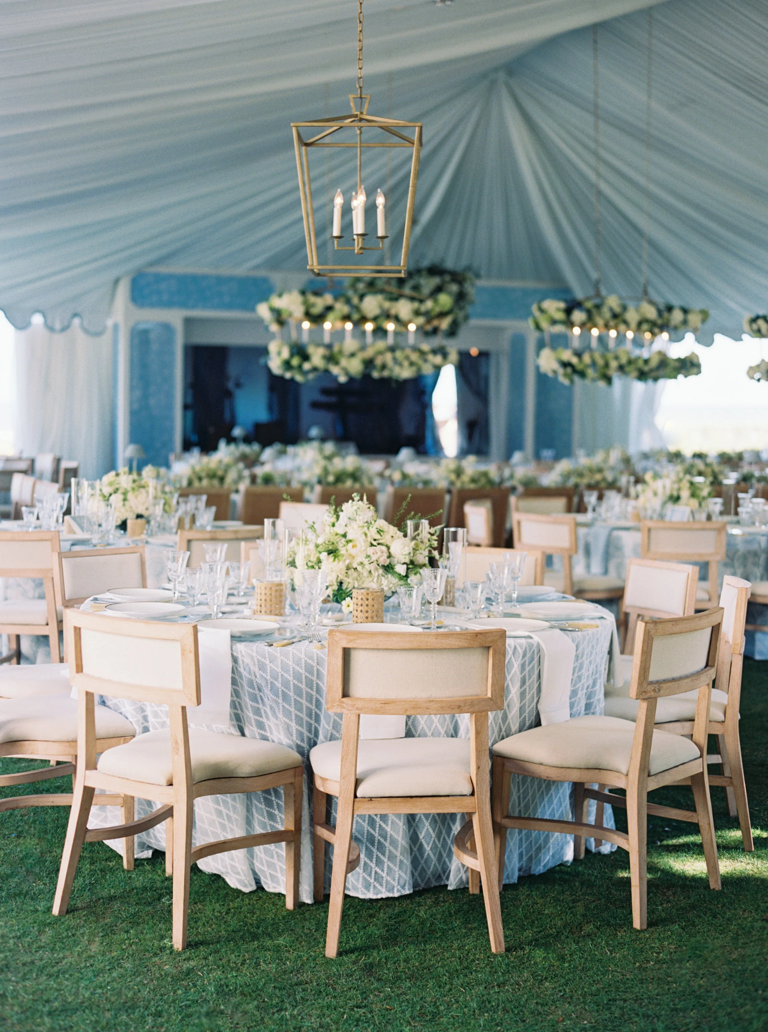 A variety of blue hues in a stunning reception design, featuring coastal prints, unique chandeliers, show-stopping florals and beautiful fabrics.