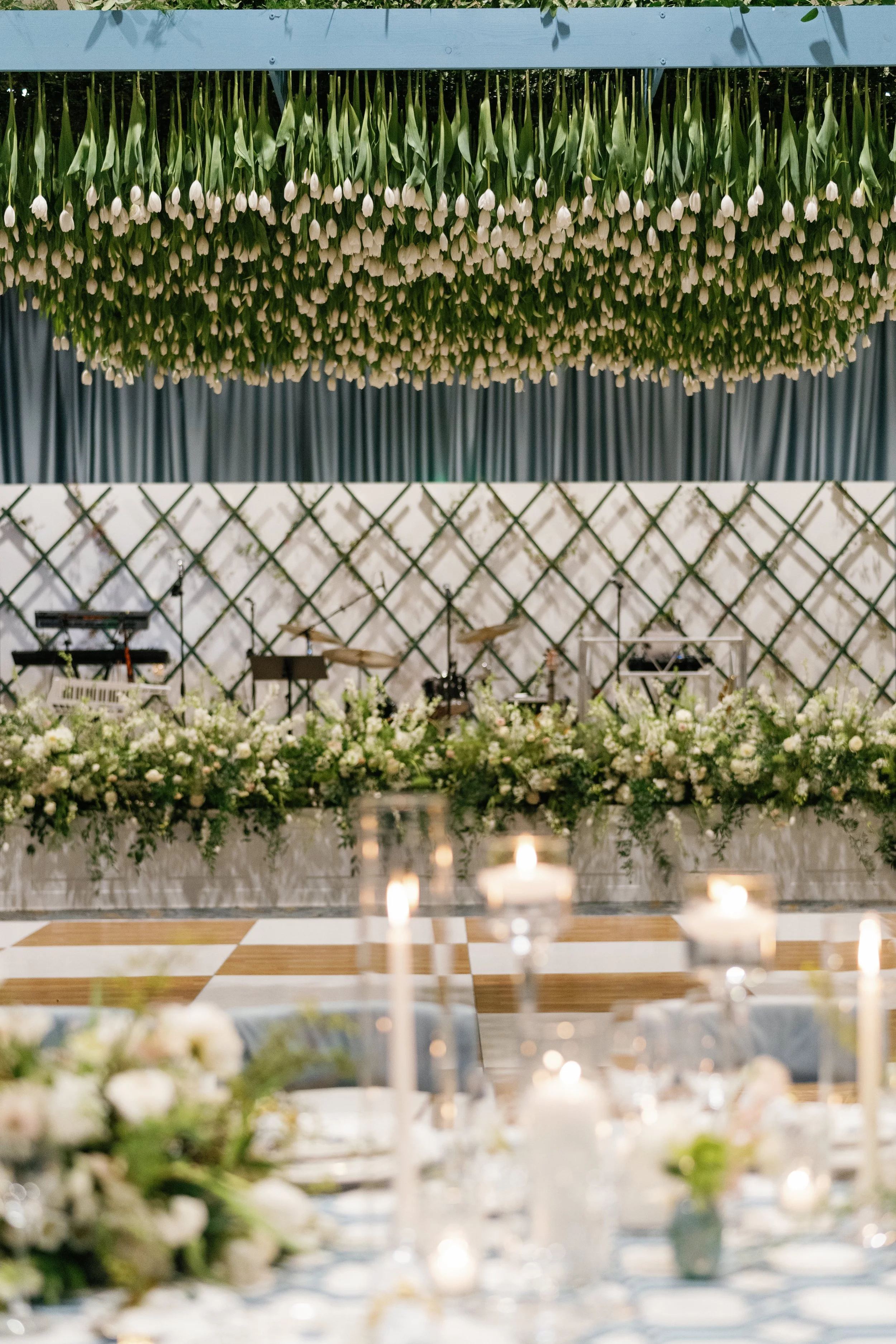 Wedding Reception where thousands of fresh tulips hang above the dance floor while a stunning floral display adorns the stage and matching blue and white tablescapes