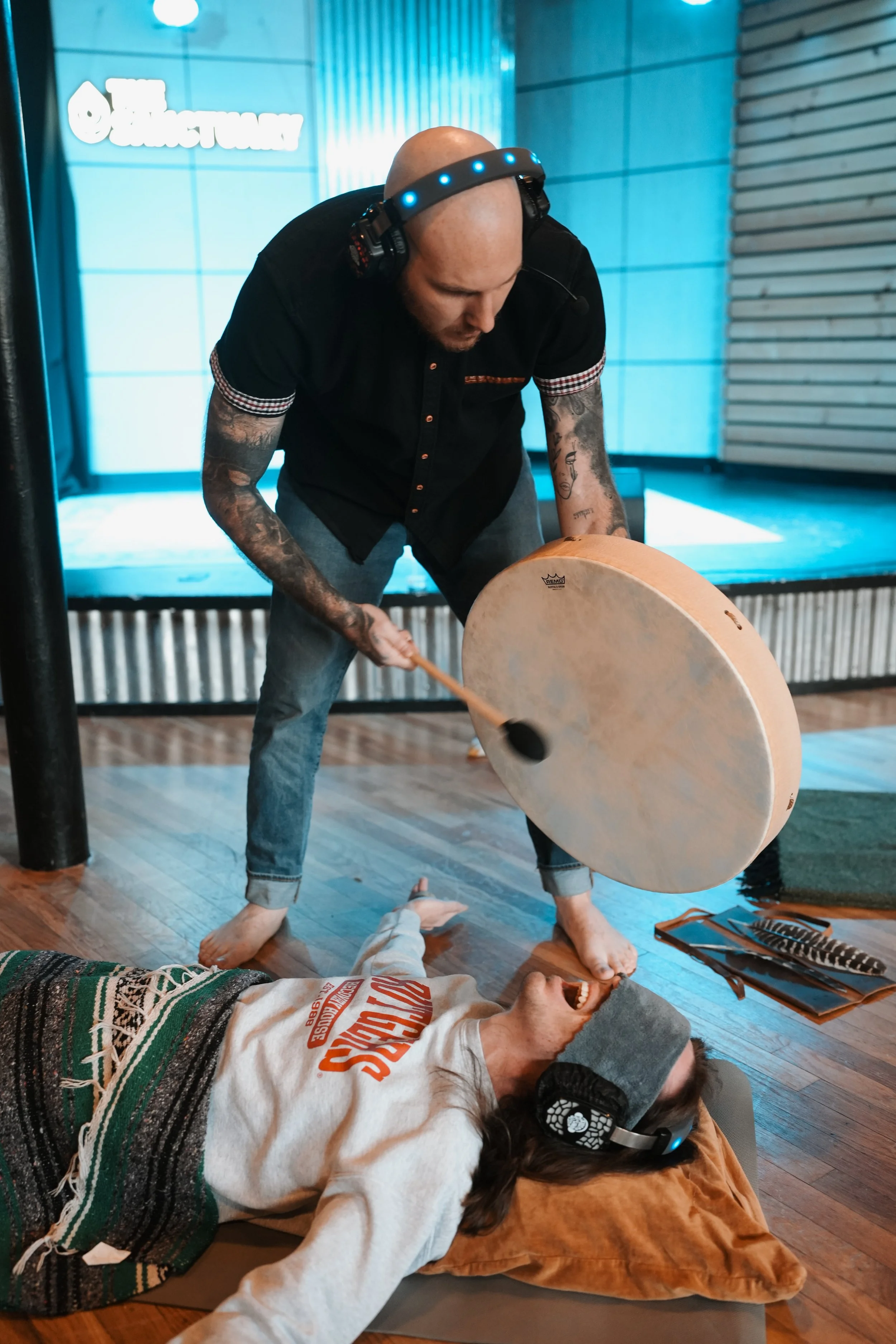 A facilitator gently plays a gong as part of a guided breathwork experience, supporting relaxation and nervous system regulation while a participant rests comfortably.