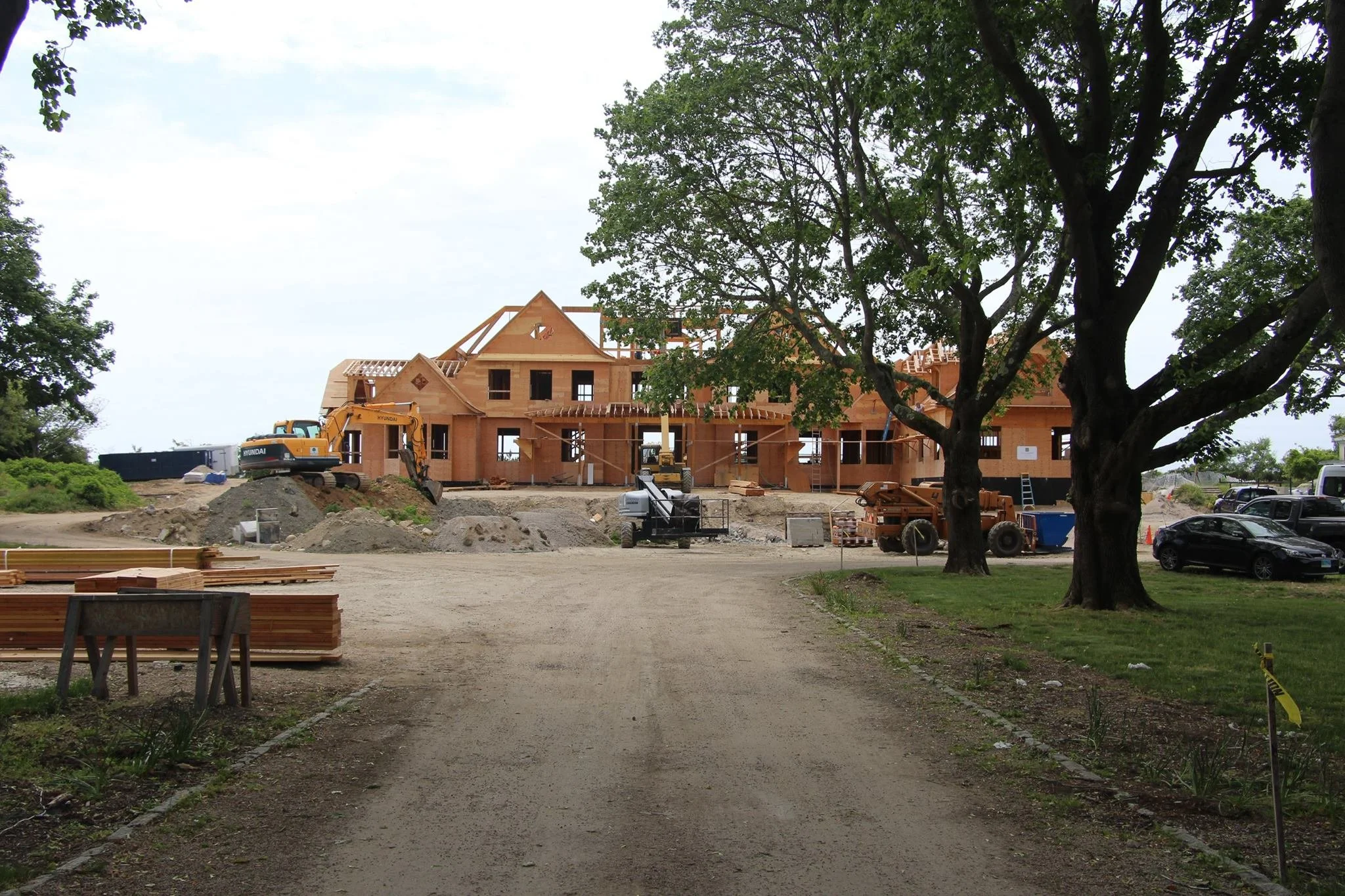 Under construction house with trees and cars nearby