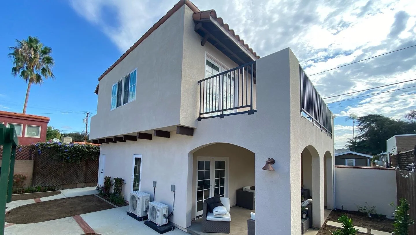 Two-story modern house with a balcony, outdoor seating area, and a landscaped backyard