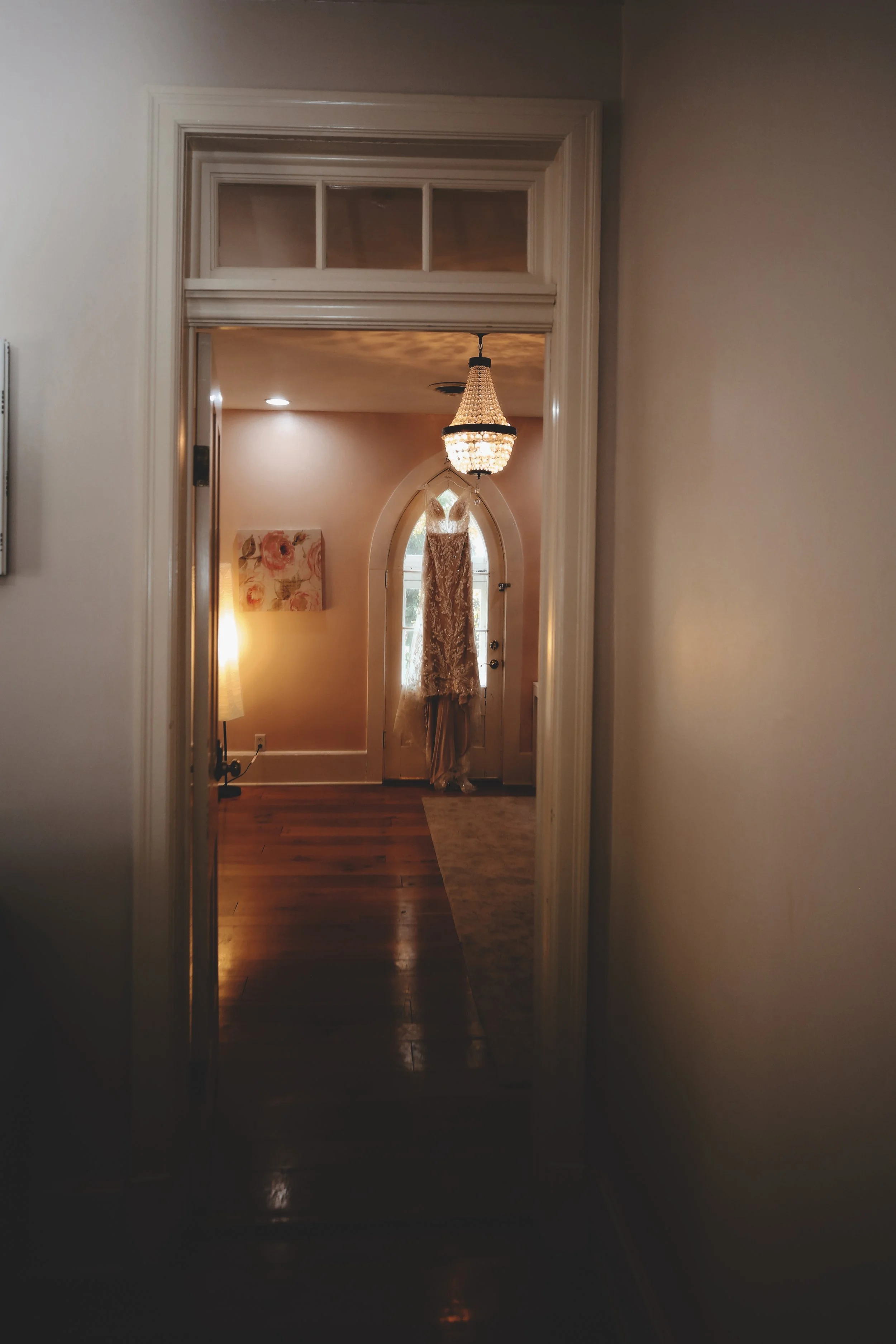 View of an entryway with a door and a lace curtain, chandelier, and artwork on the wall.