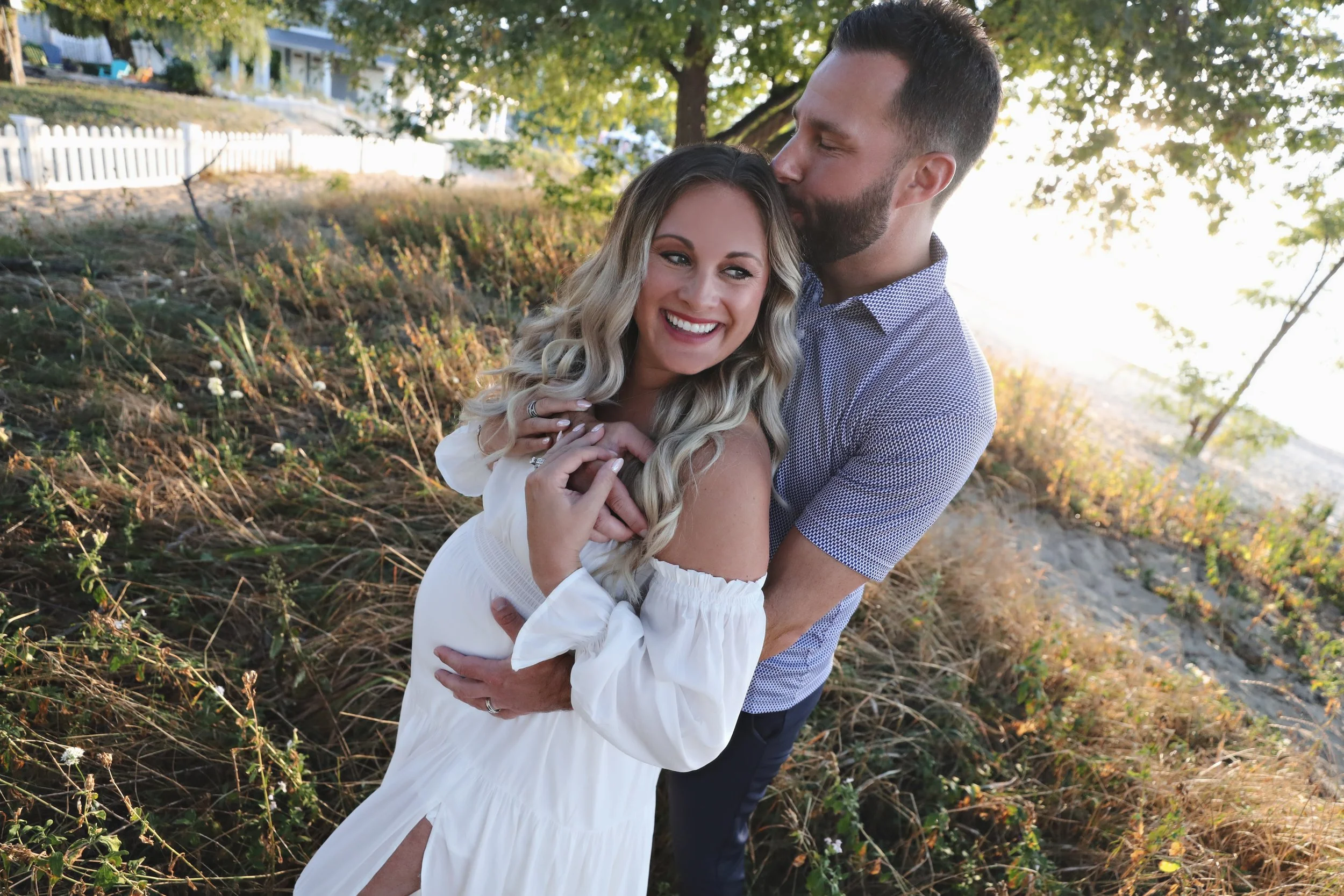 A happy couple embracing outdoors during sunset, smiling and looking at each other.
