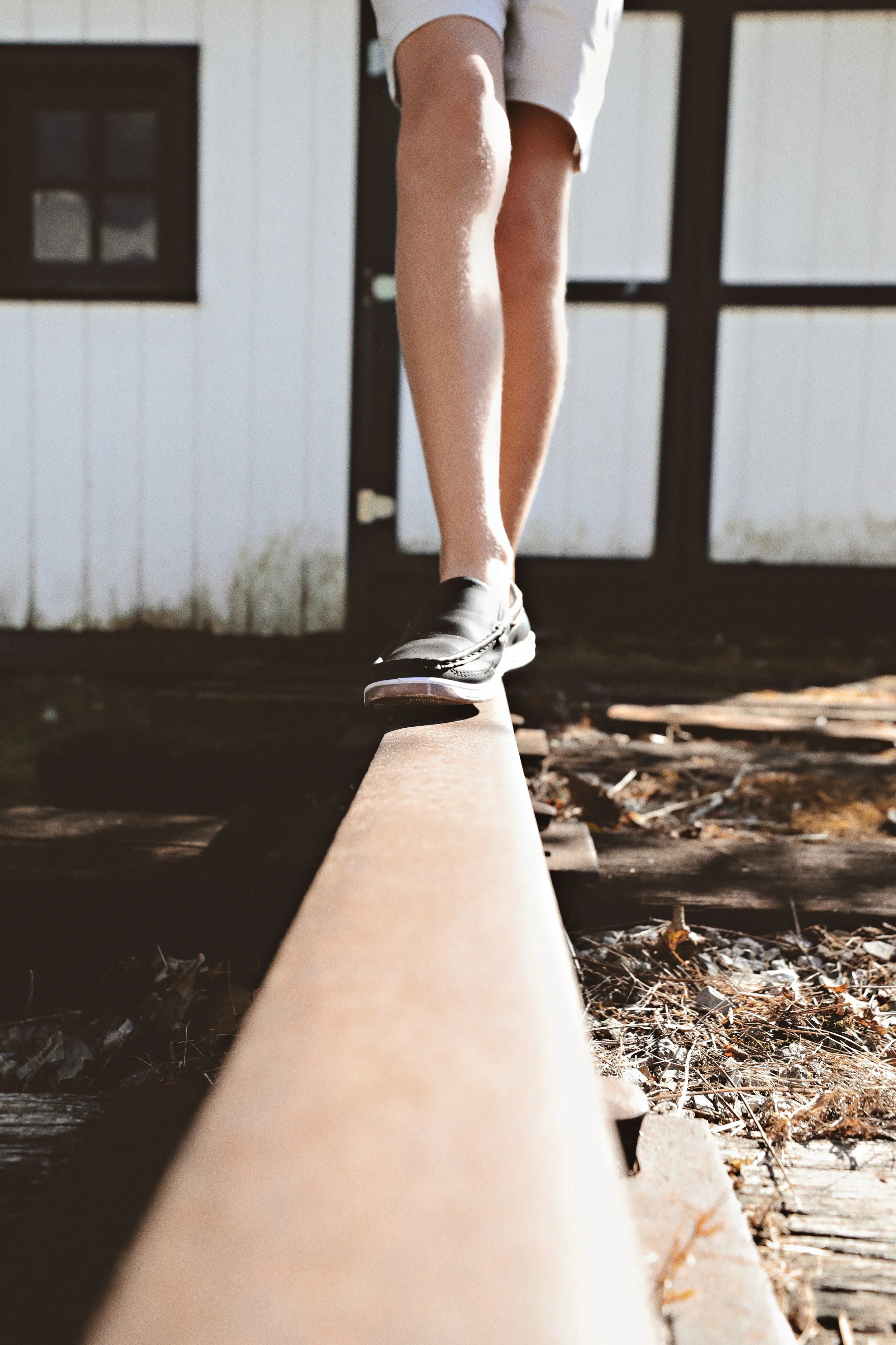 Person walking on a railway track wearing black shoes and white shorts, captured from a low angle.