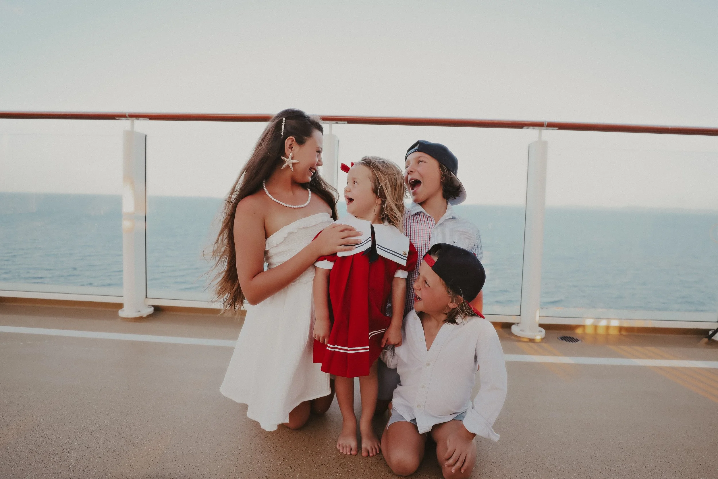 A woman and four children on the deck of a ship, with the ocean in the background, happily laughing and sharing a moment.