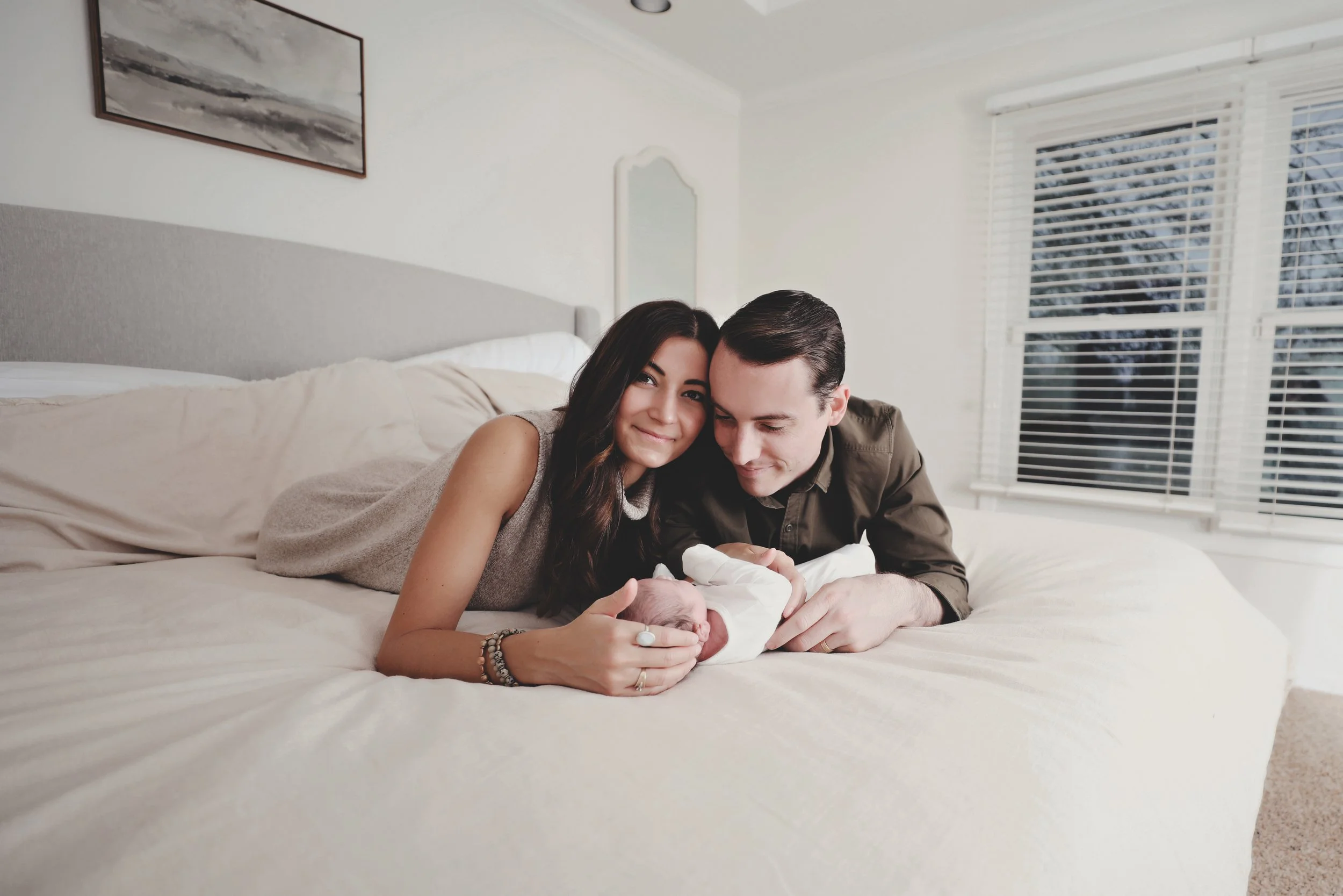 New parents lying on their bed holding their newborn baby
