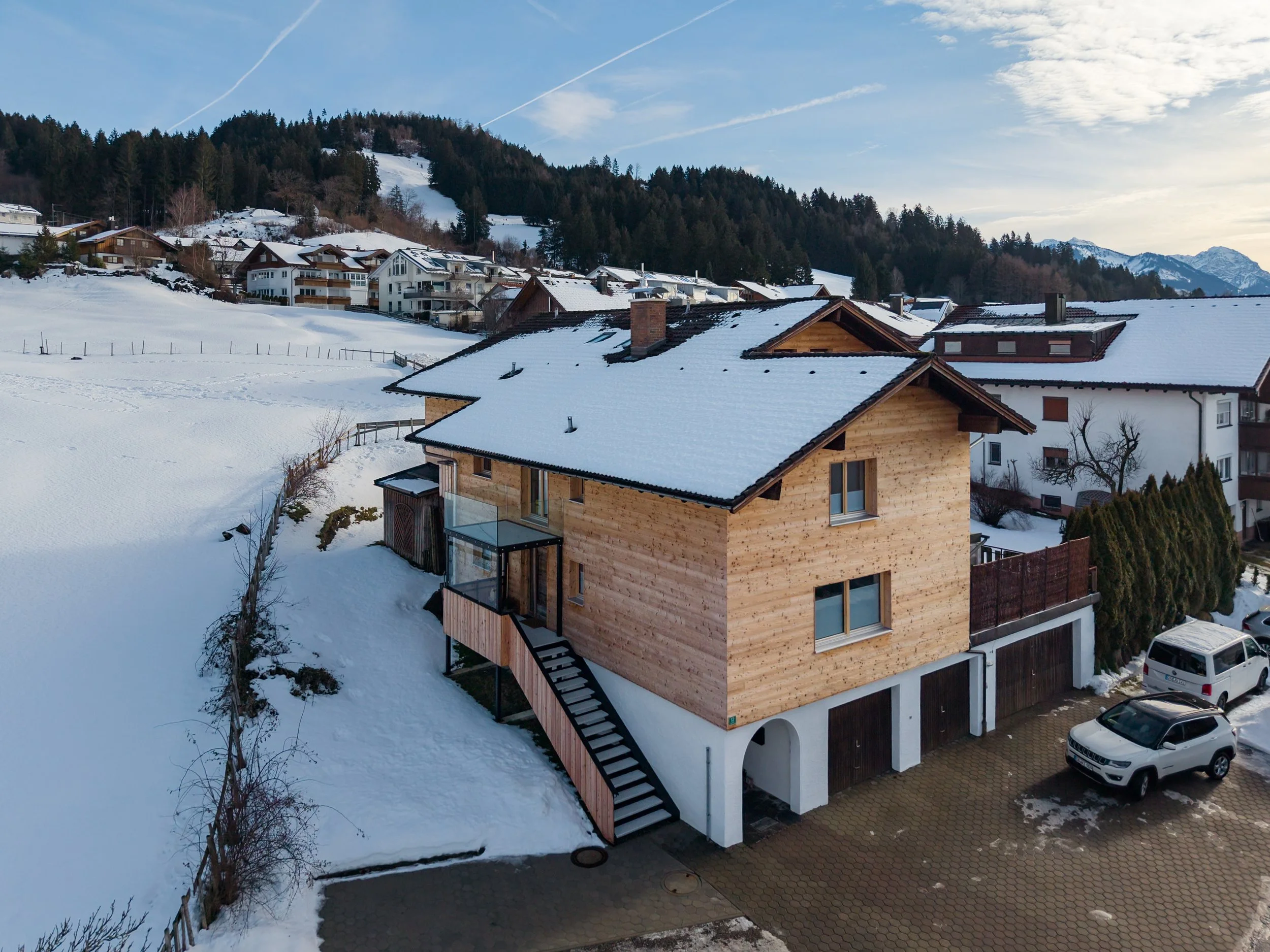 Häuser im Winter auf einem schneebedeckten Hügel in einer bergigen Landschaft