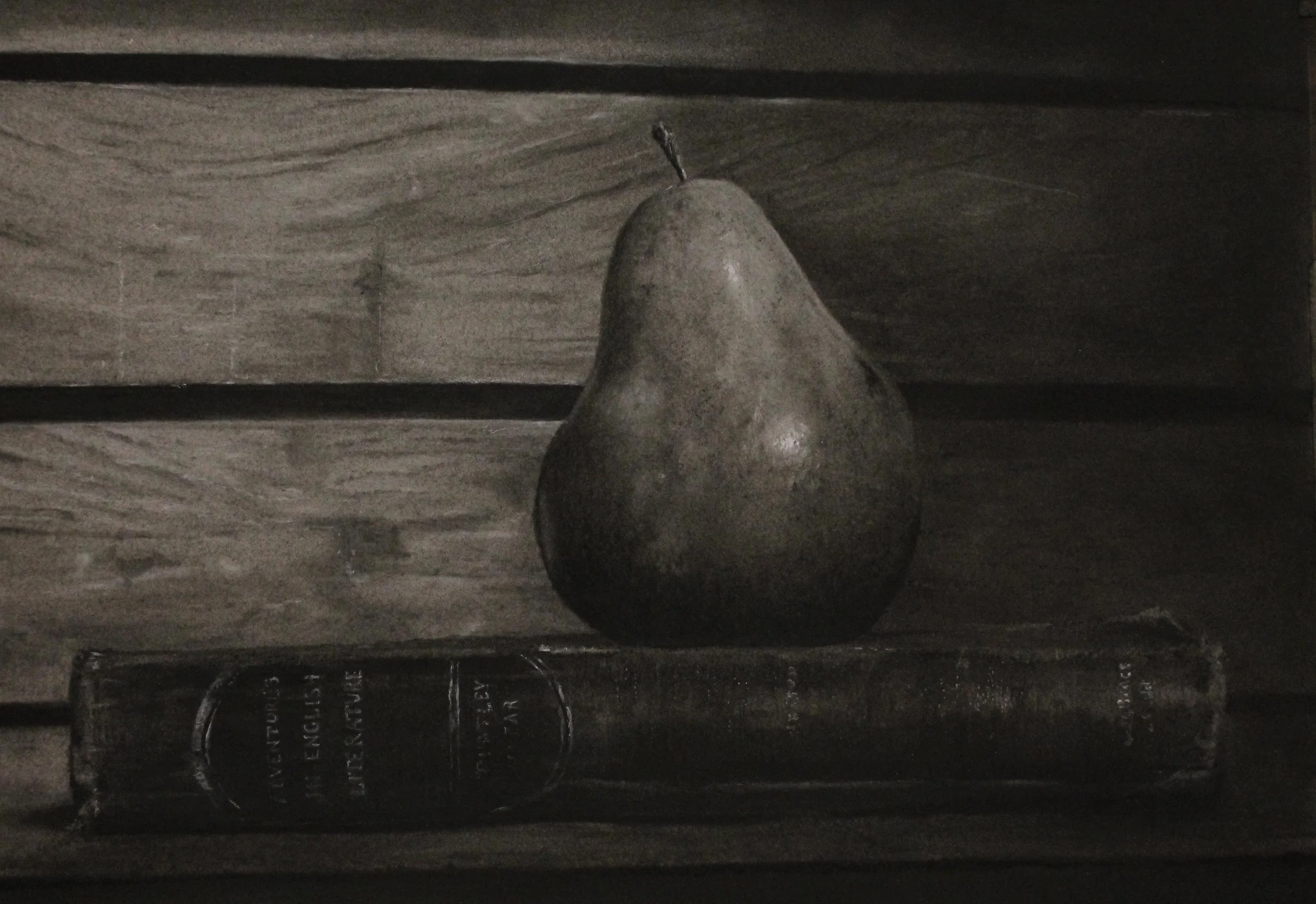 A single pear sitting on top of a closed book with worn out spine, on a wooden surface.