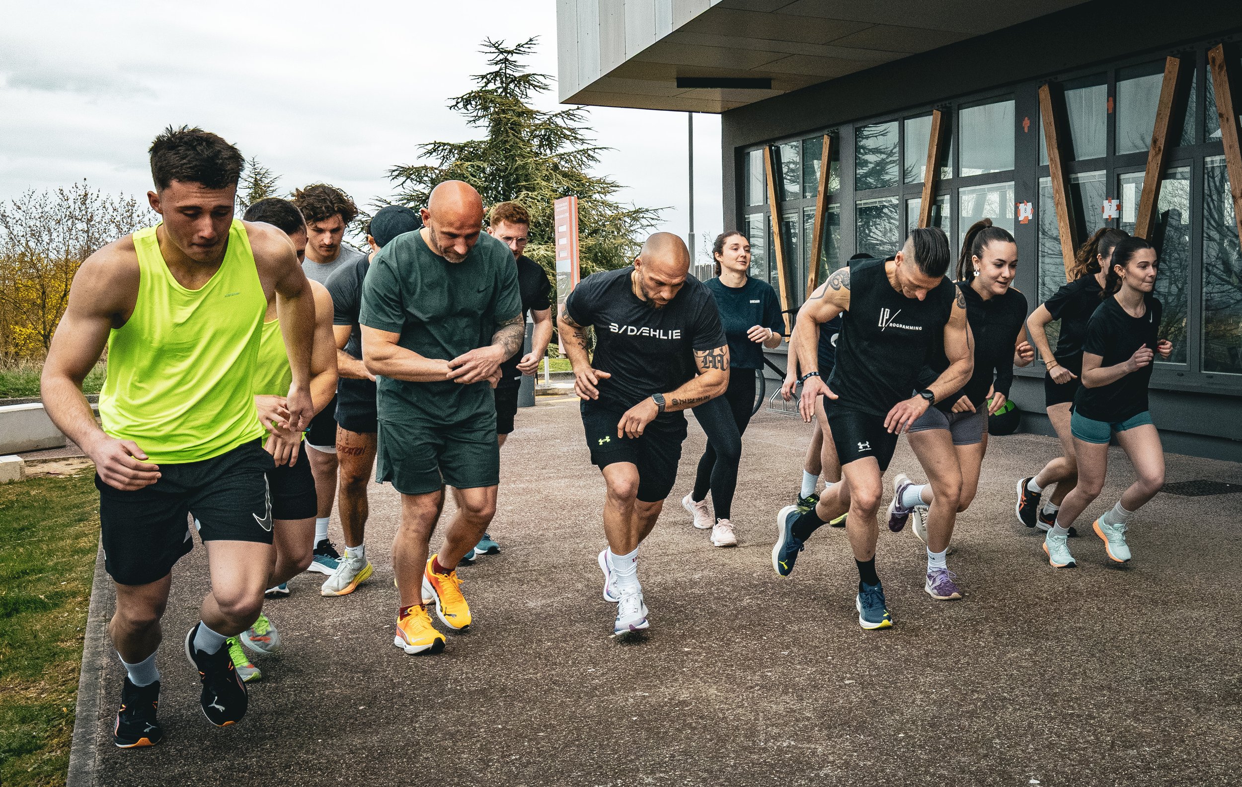 Groupe de personnes en entraînement de course ou de fitness dehors devant un bâtiment moderne. course hyrox, événement hyrox dijon