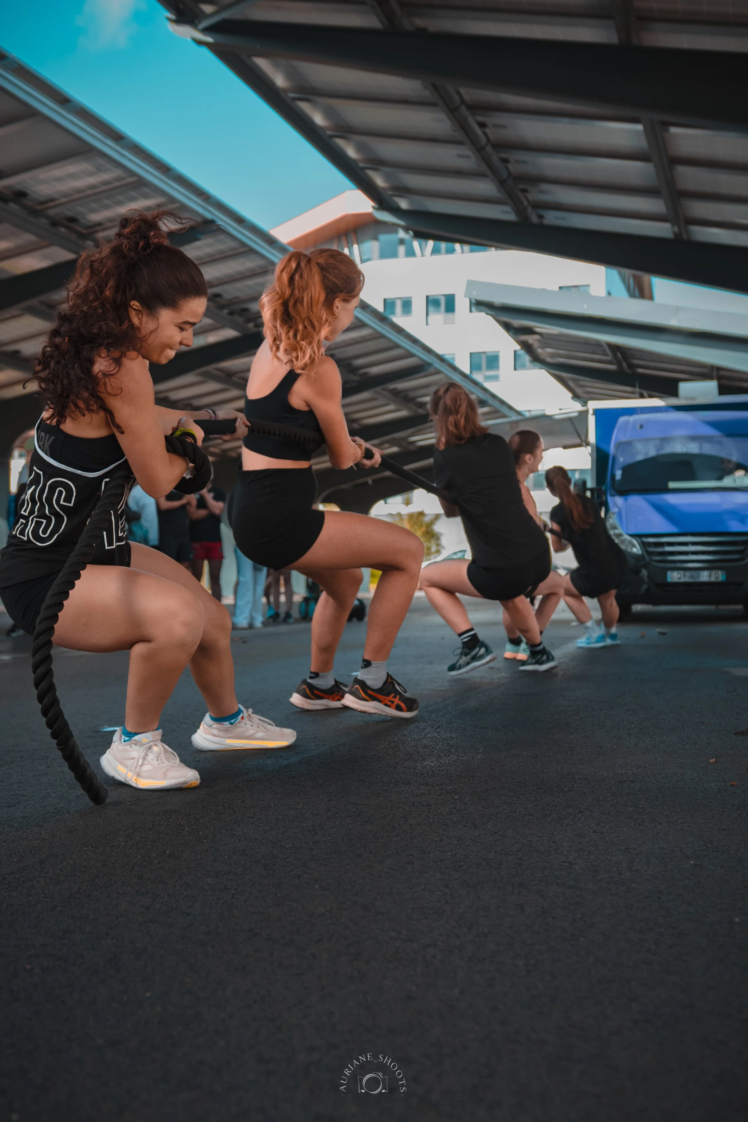 Groupe de femmes faisant des exercices de tractions avec une corde dans une zone couverte d'un parking