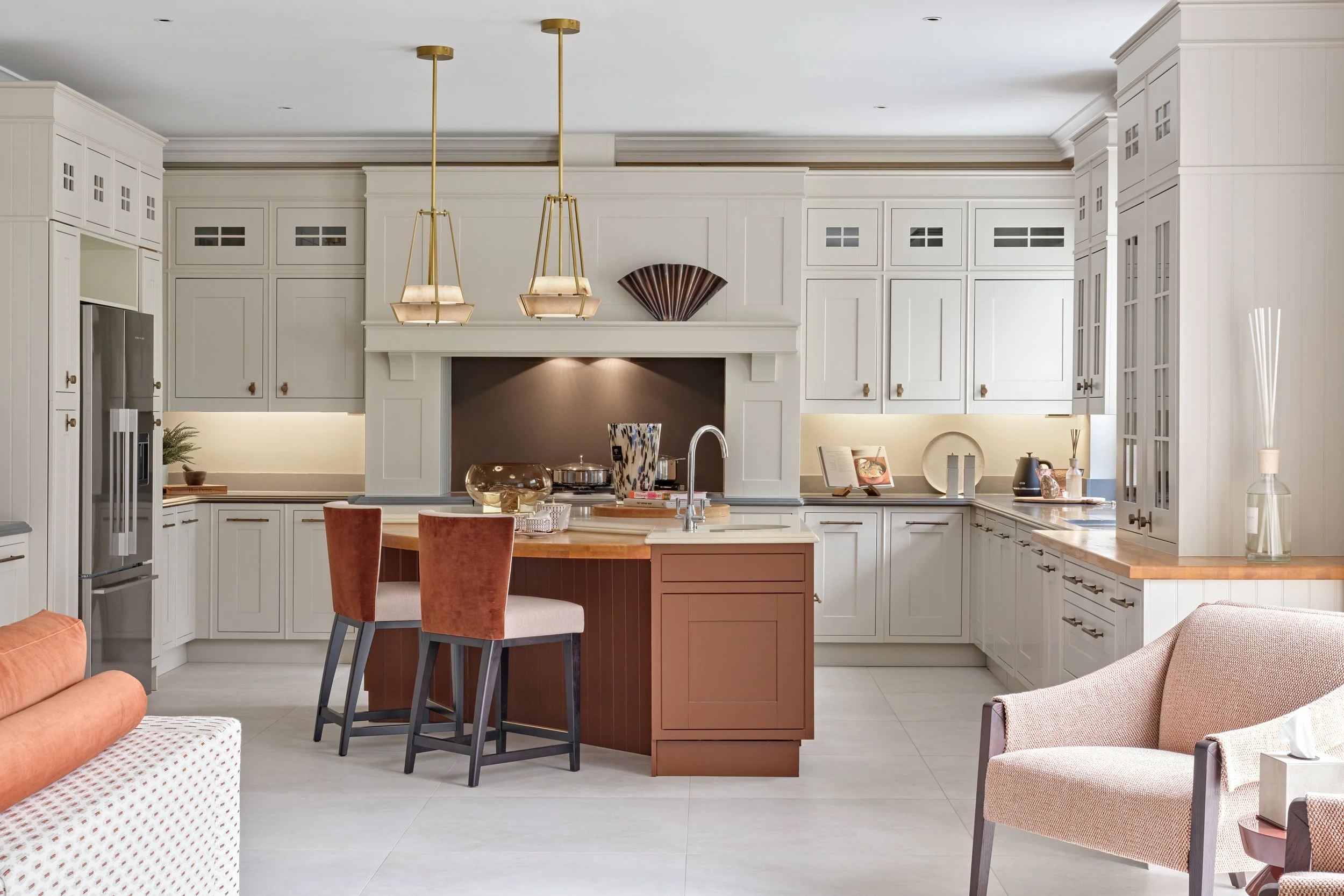 Modern kitchen with white cabinetry, a central island with a brown base, pendant lighting, and various decor items.