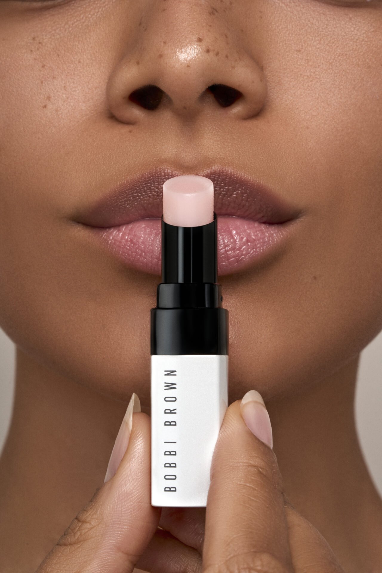 Nahaufnahme eines schönen Mundes mit Lippenstift, der während des Auftragens eines Bobbi Brown Lippenpflegestiftes gehalten wird.
