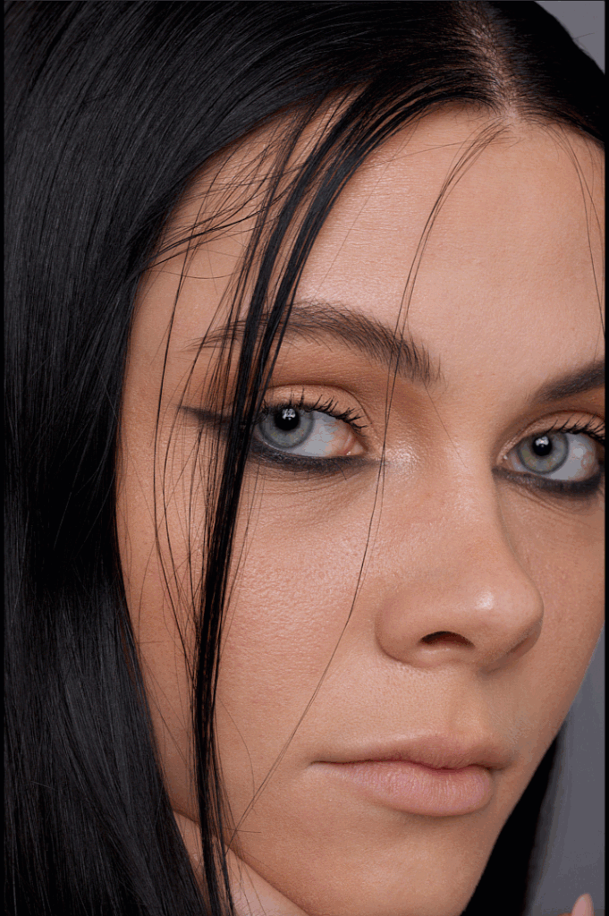 Nahaufnahme eines Mädchens mit schwarzen Haaren und blauen Augen, Blick seitlich.